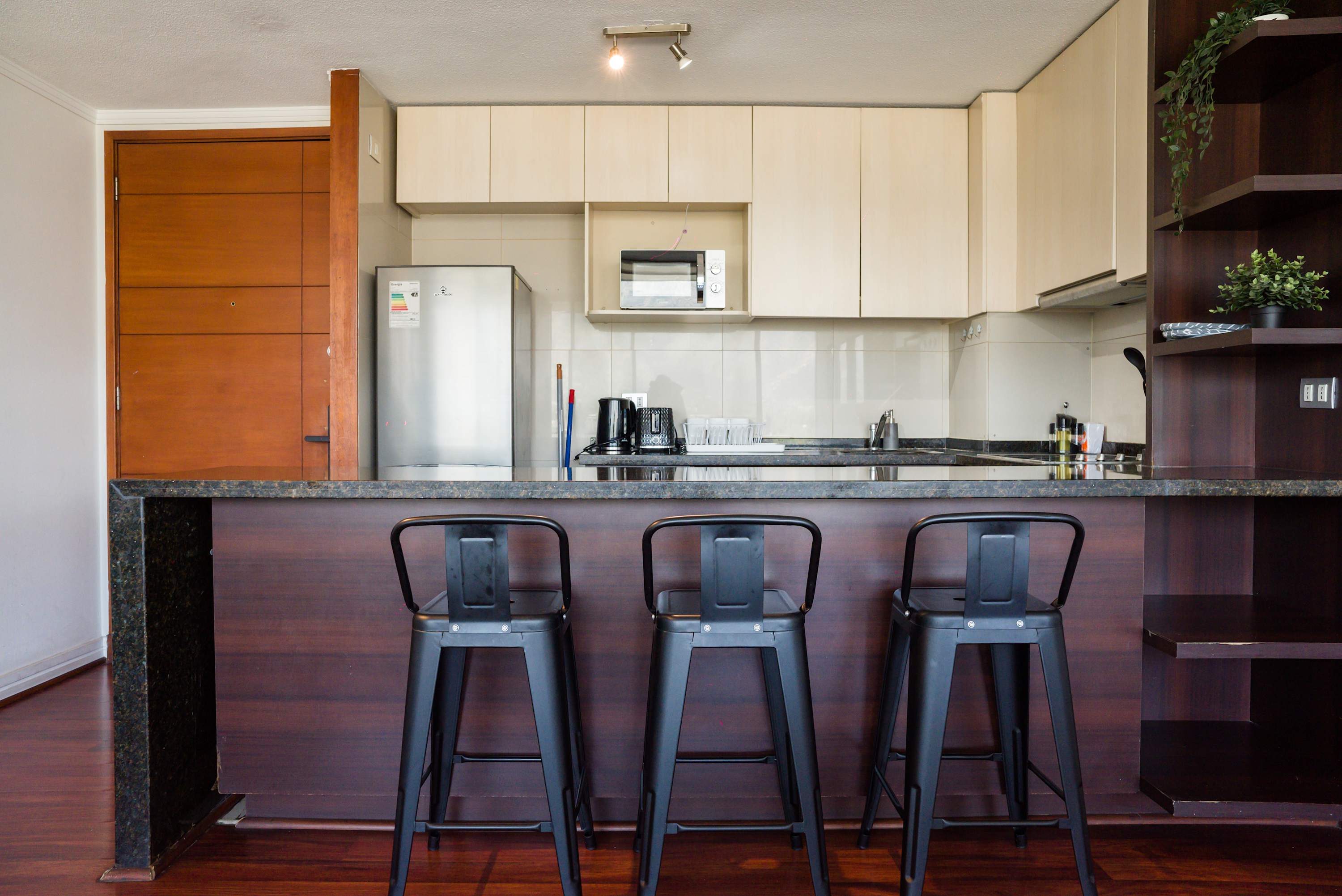 Fully equipped kitchen with a granite breakfast peninsula, three bar stools, stainless-steel appliances, and convenient countertop essentials.