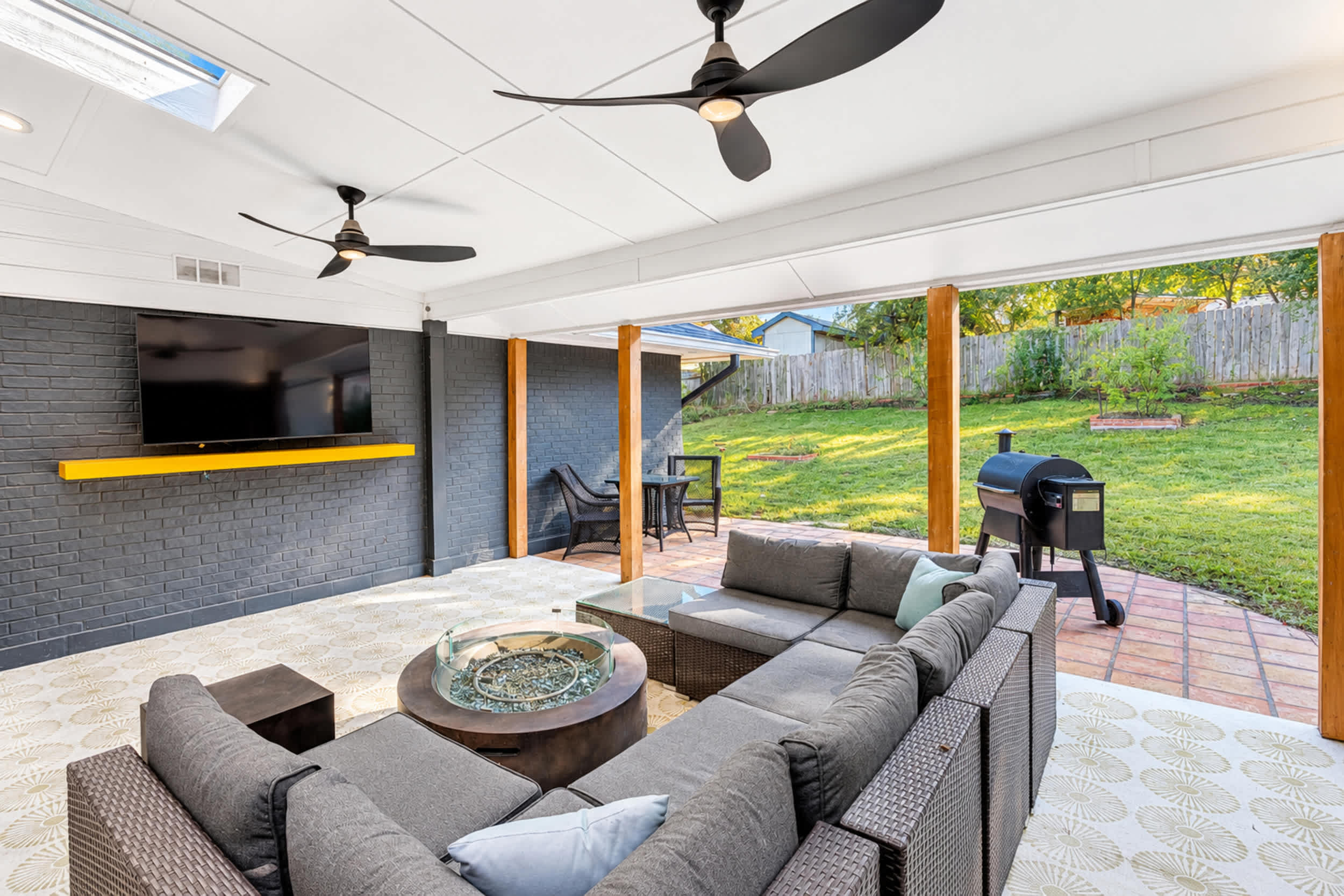 Covered outdoor living space with comfortable sectional seating, a gas fire pit, and a mounted smart TV