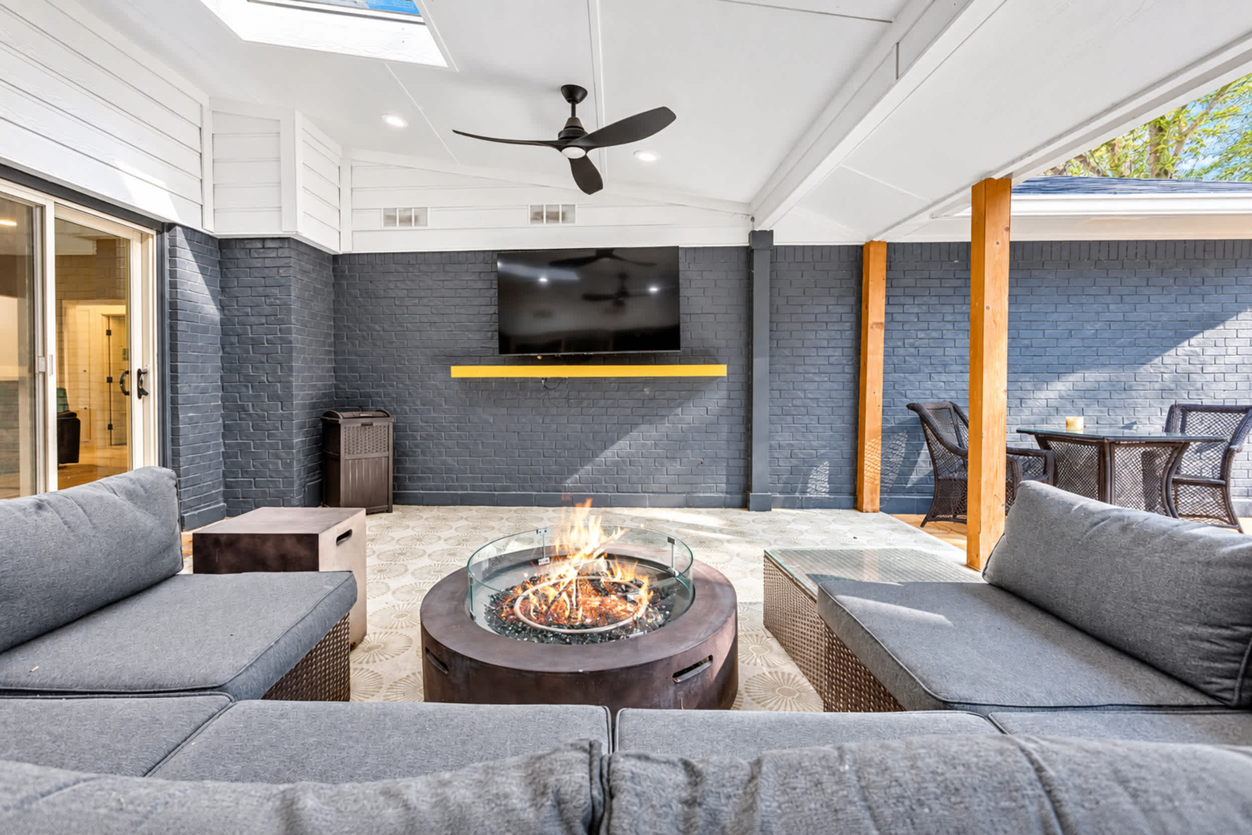 Covered outdoor living space with comfortable sectional seating, a gas fire pit, and a mounted smart TV
