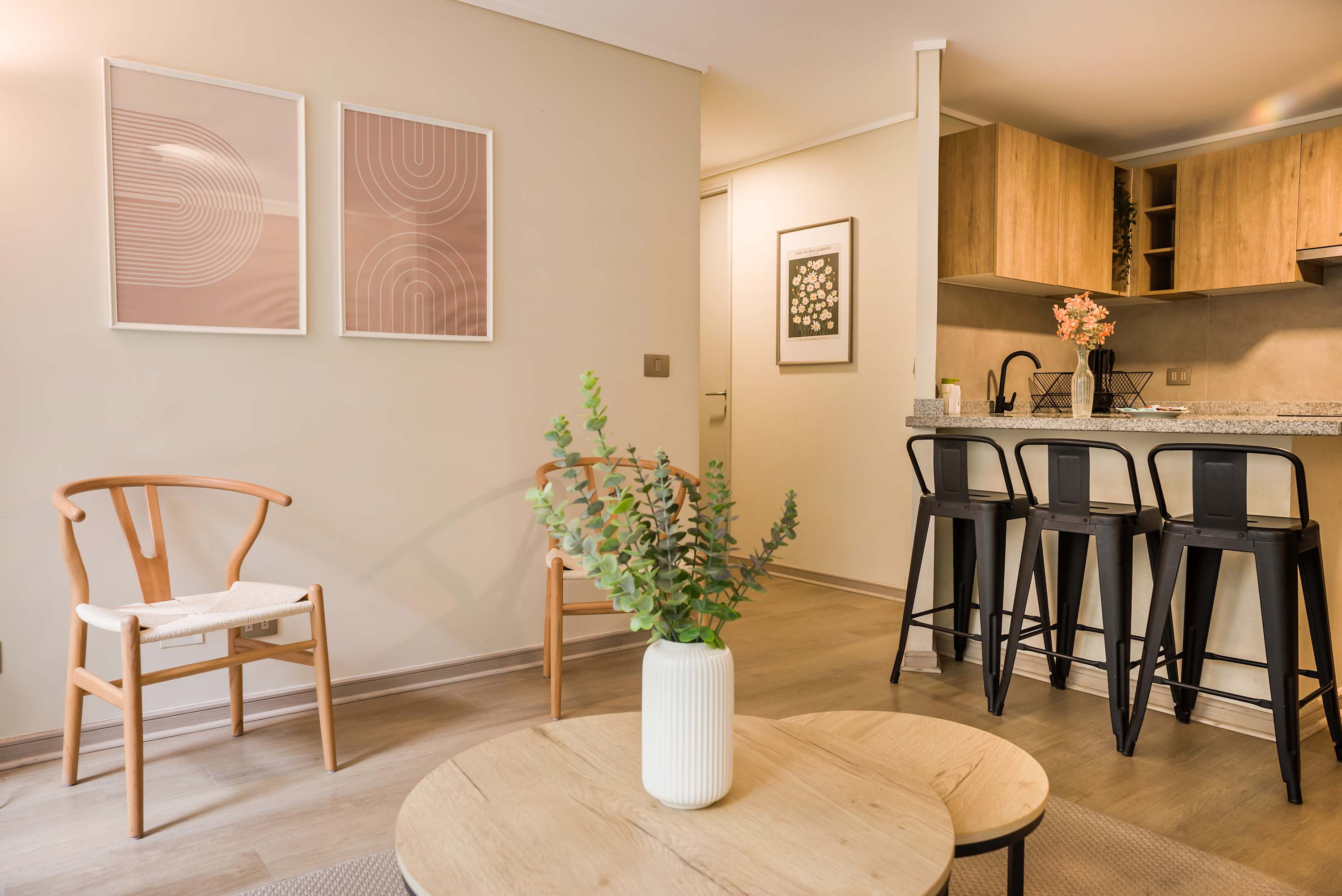 Open-plan dining area with seating for five, a warm wood kitchen, and a round table styled with greenery.