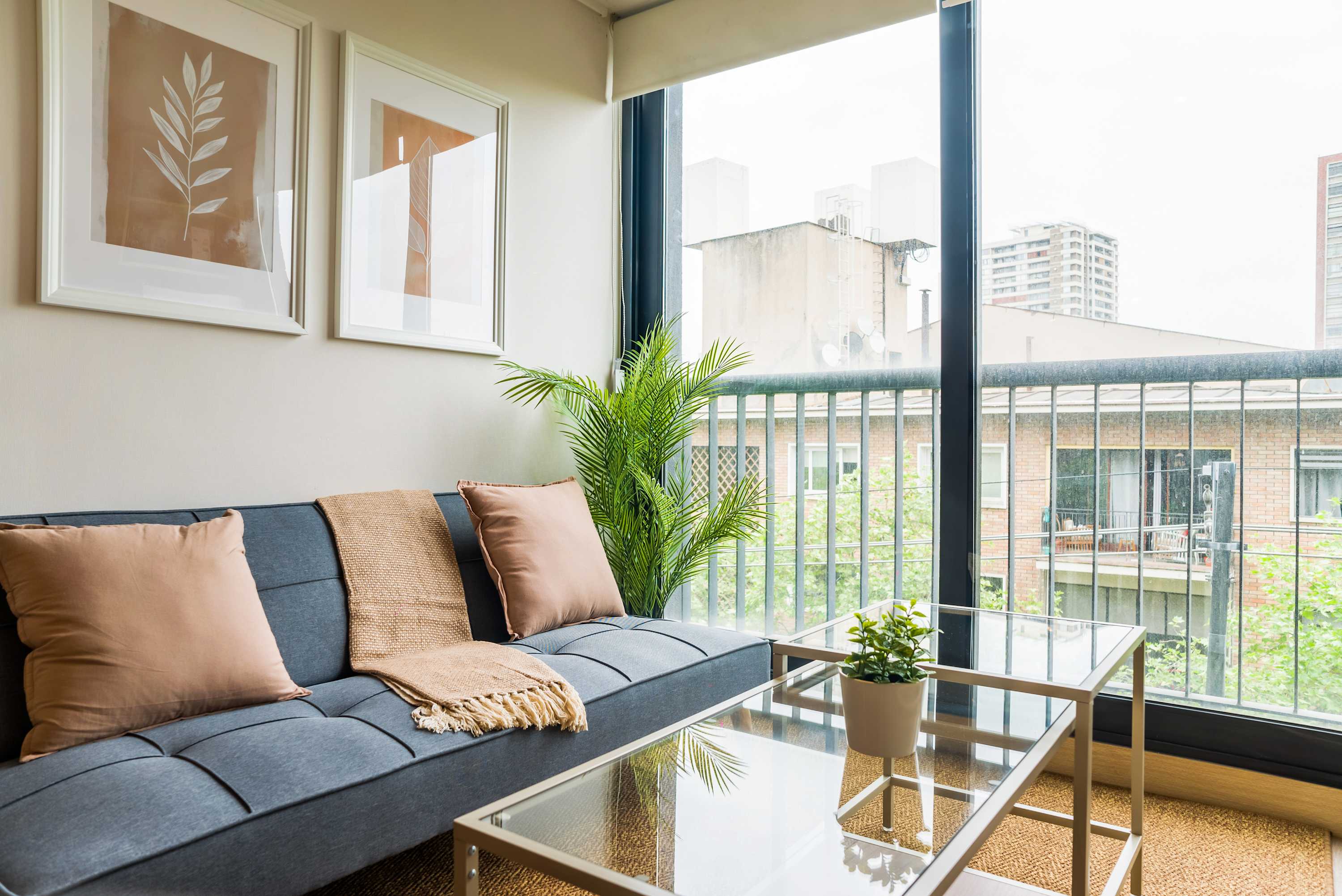 Bright living room with a blue-gray sectional, woven throw, and floor-to-ceiling windows overlooking the city.