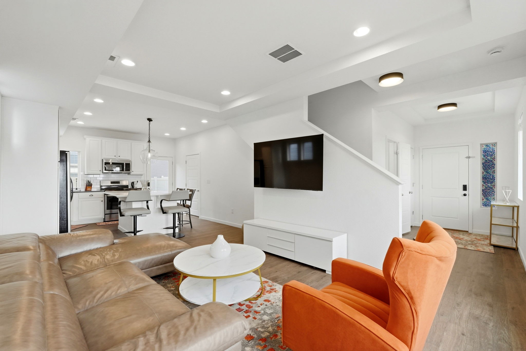Open-concept living room with a large wall-mounted TV that flows right into the kitchen
