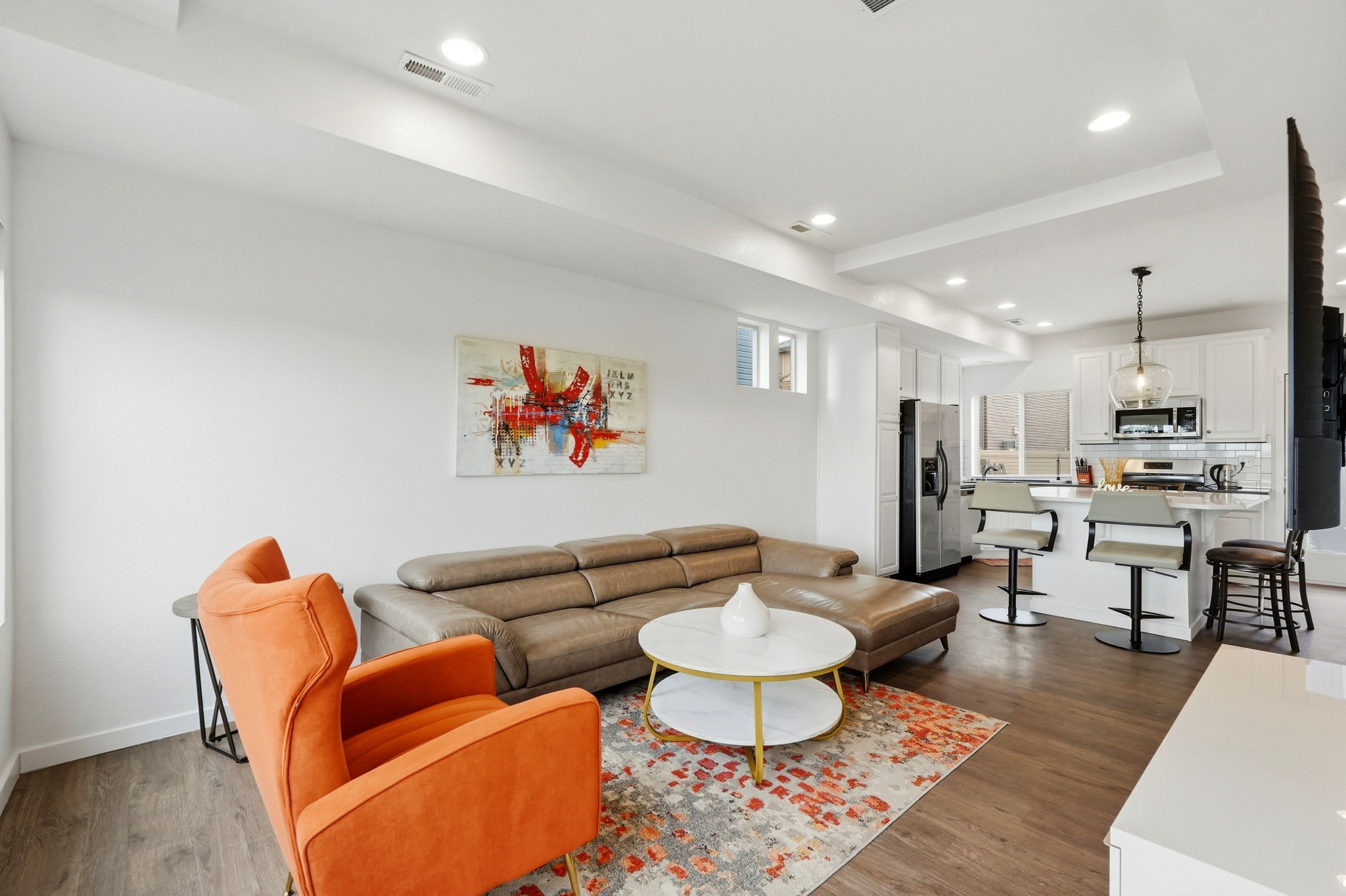 Cozy living room with a leather sectional and accent chair, open to the kitchen