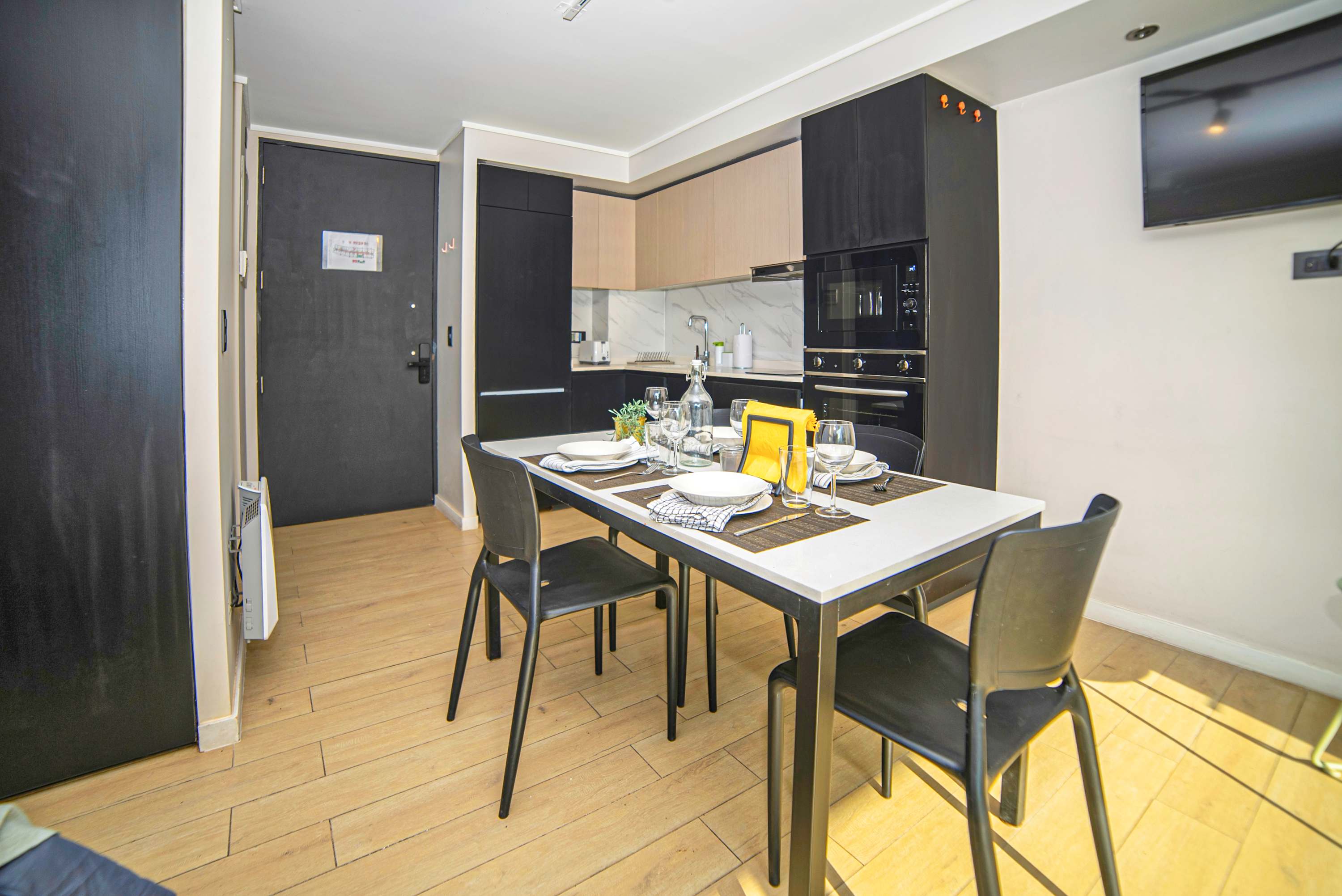 Private dining area with a four-seat table set for meals beside a fully equipped modern kitchen.