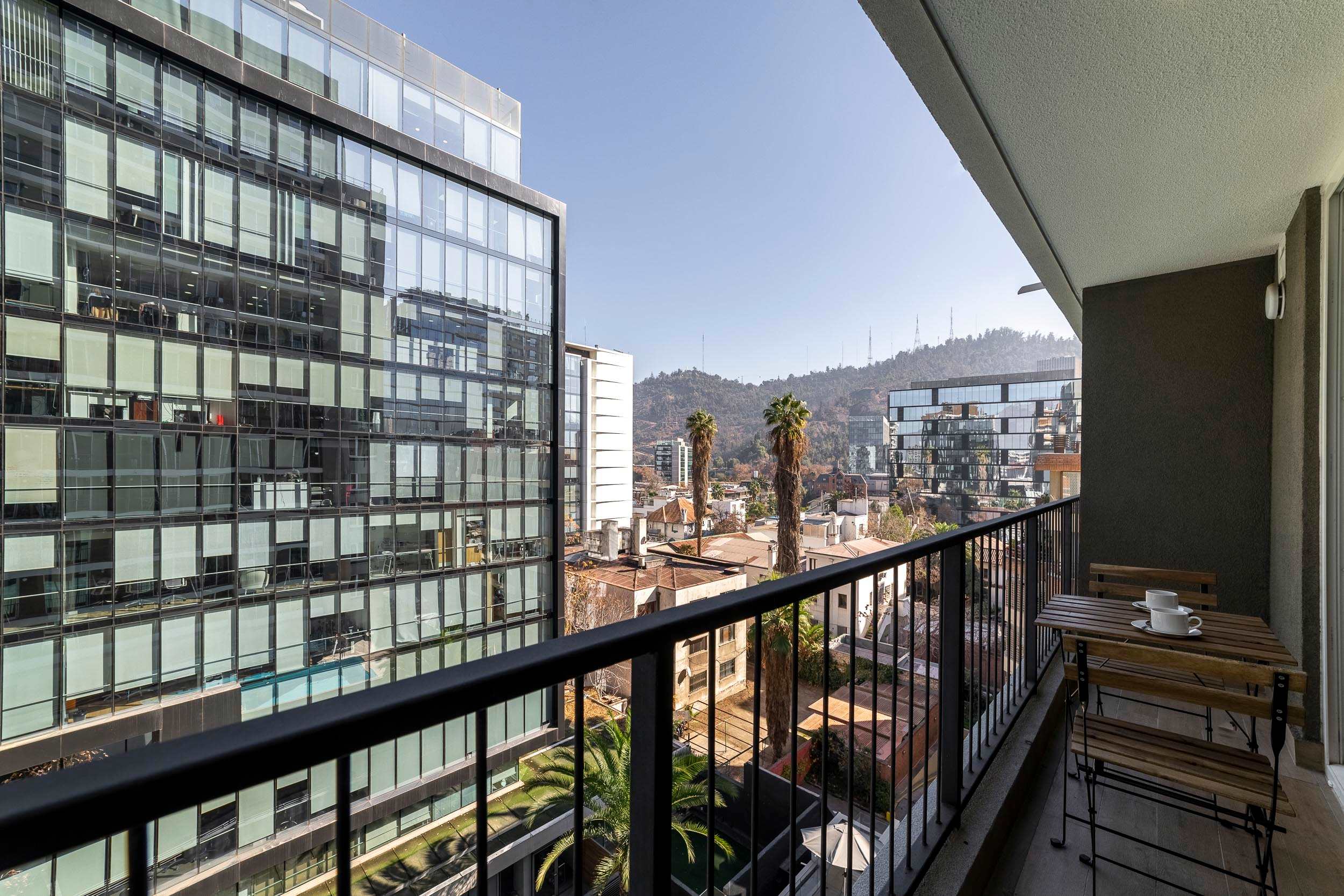 Enjoy morning coffee for two on the private balcony, with sweeping views of Santiago’s modern skyline, palm trees, and wooded hills.