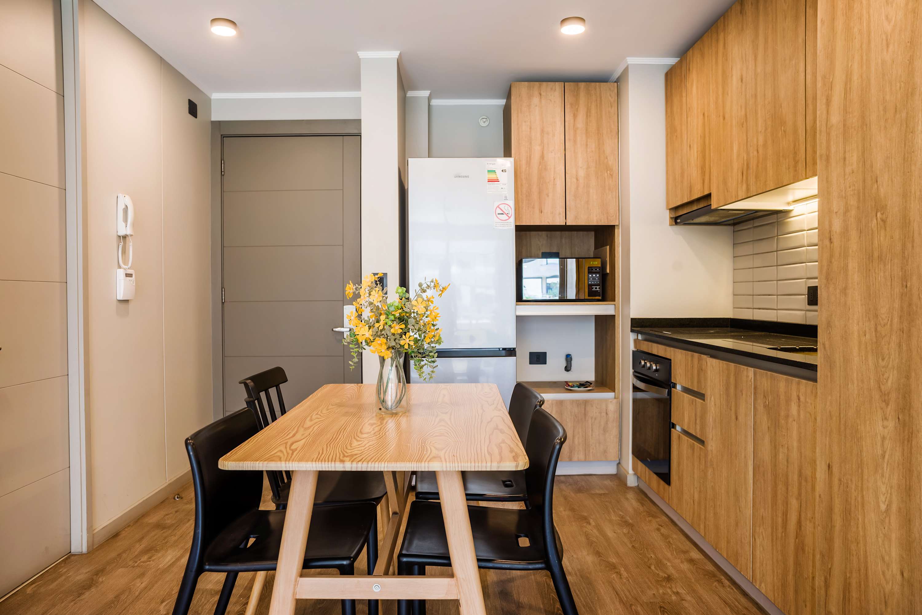 Private dining area with seating for five, a solid wood table, and a fully equipped kitchen with modern built-in appliances.