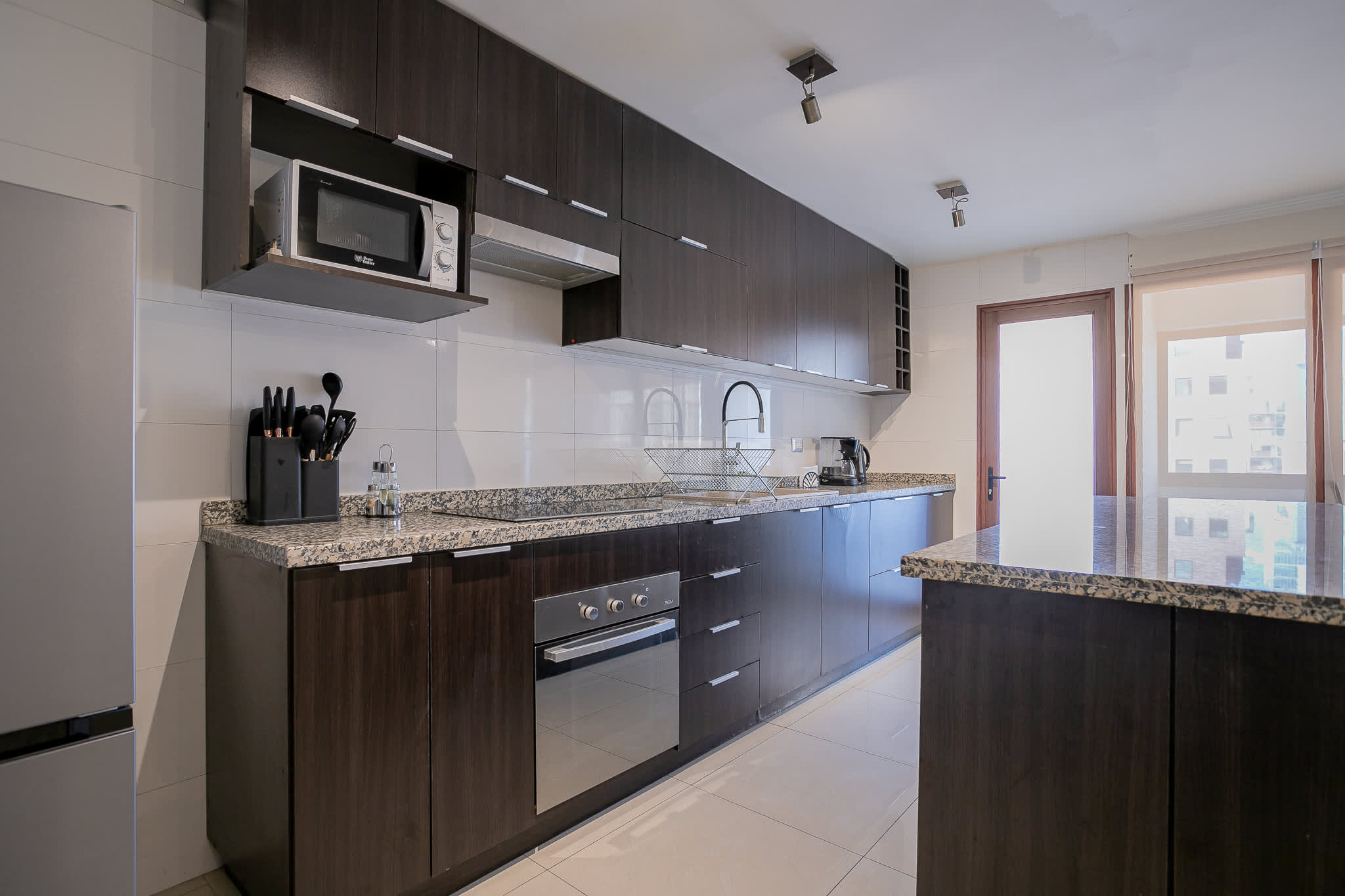 Private kitchen with a full suite of appliances, granite countertops, and a spacious island overlooking the city-facing window.