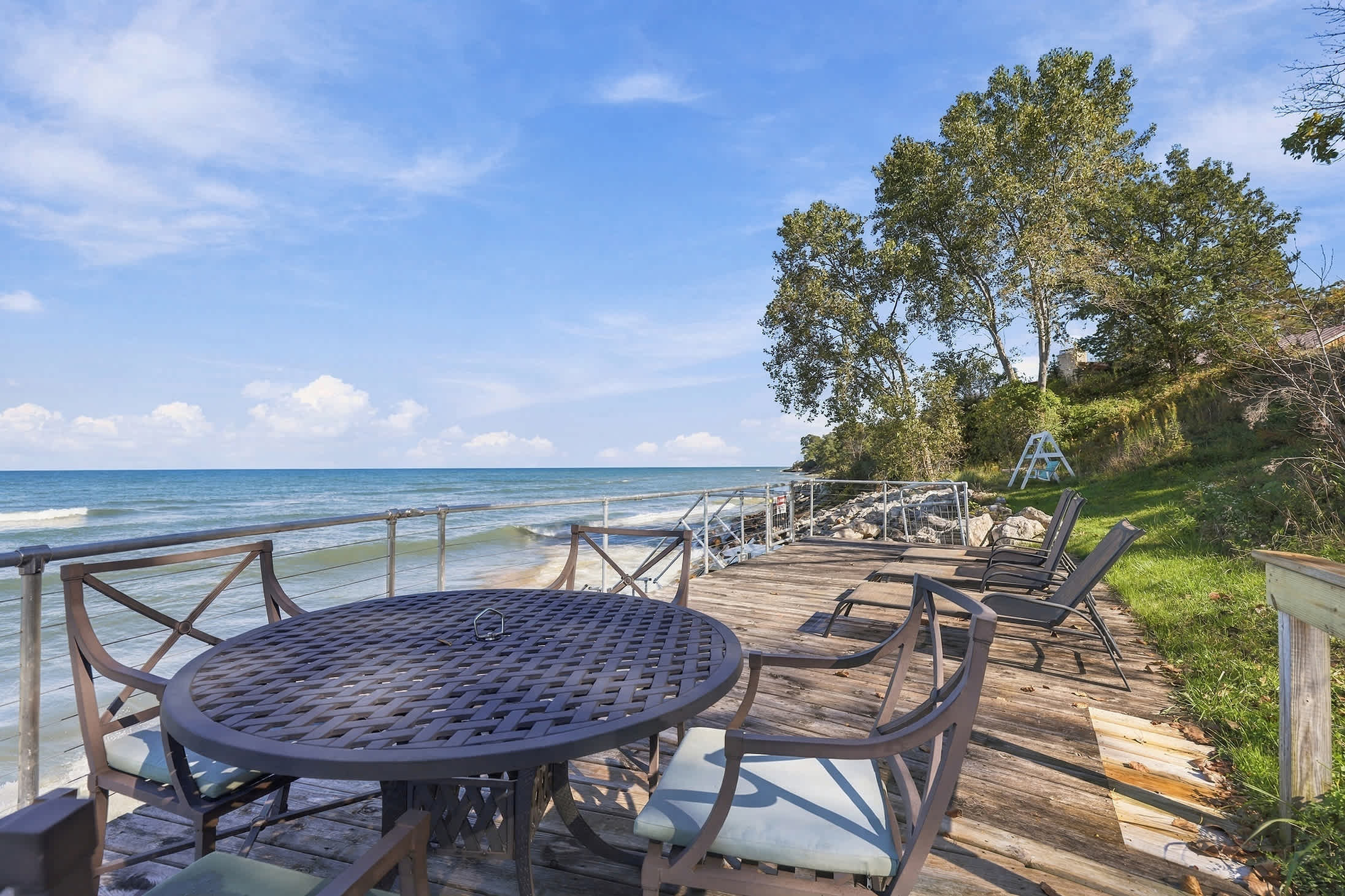 Lake Michigan waterfront deck with patio dining and loungers by the shore.