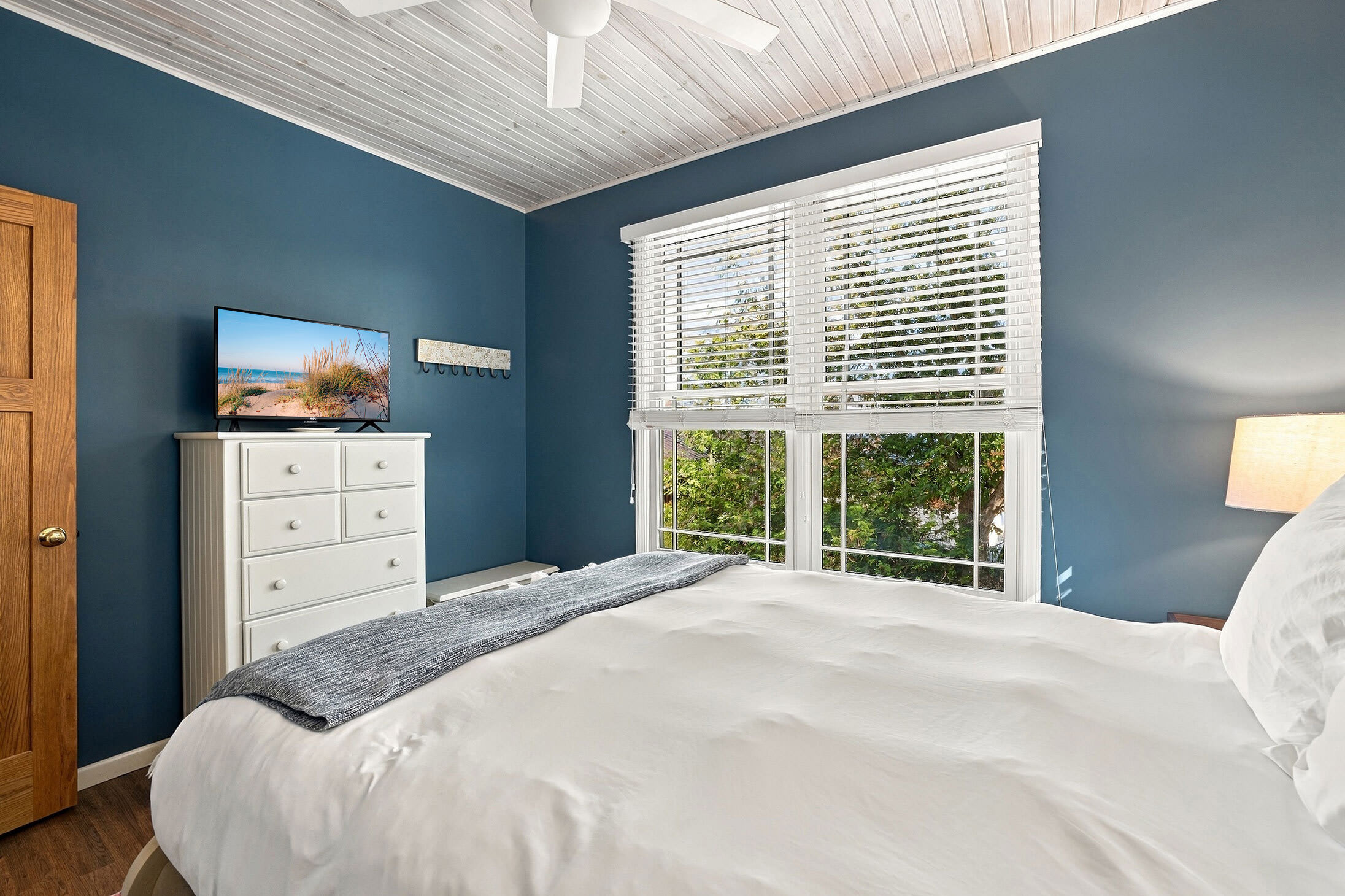 Calm blue bedroom with ceiling fan, TV, and room to unpack for the week