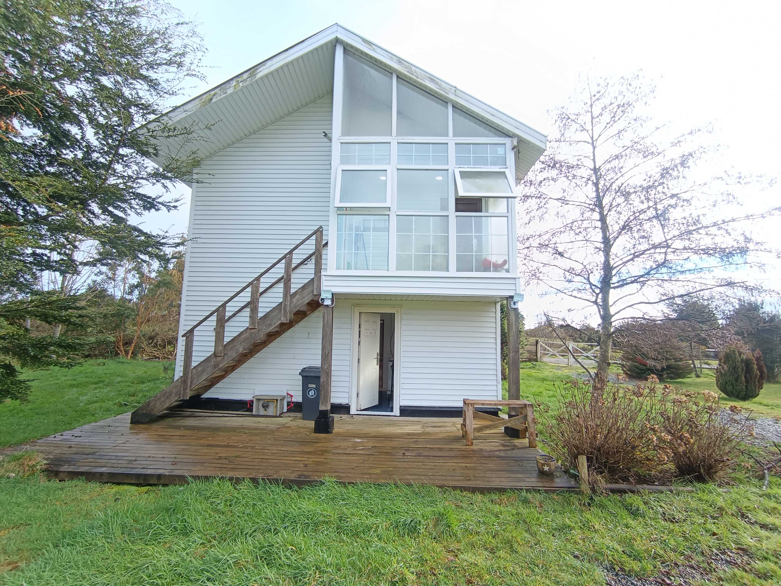 House exterior with large glazed upper level and wooden deck
