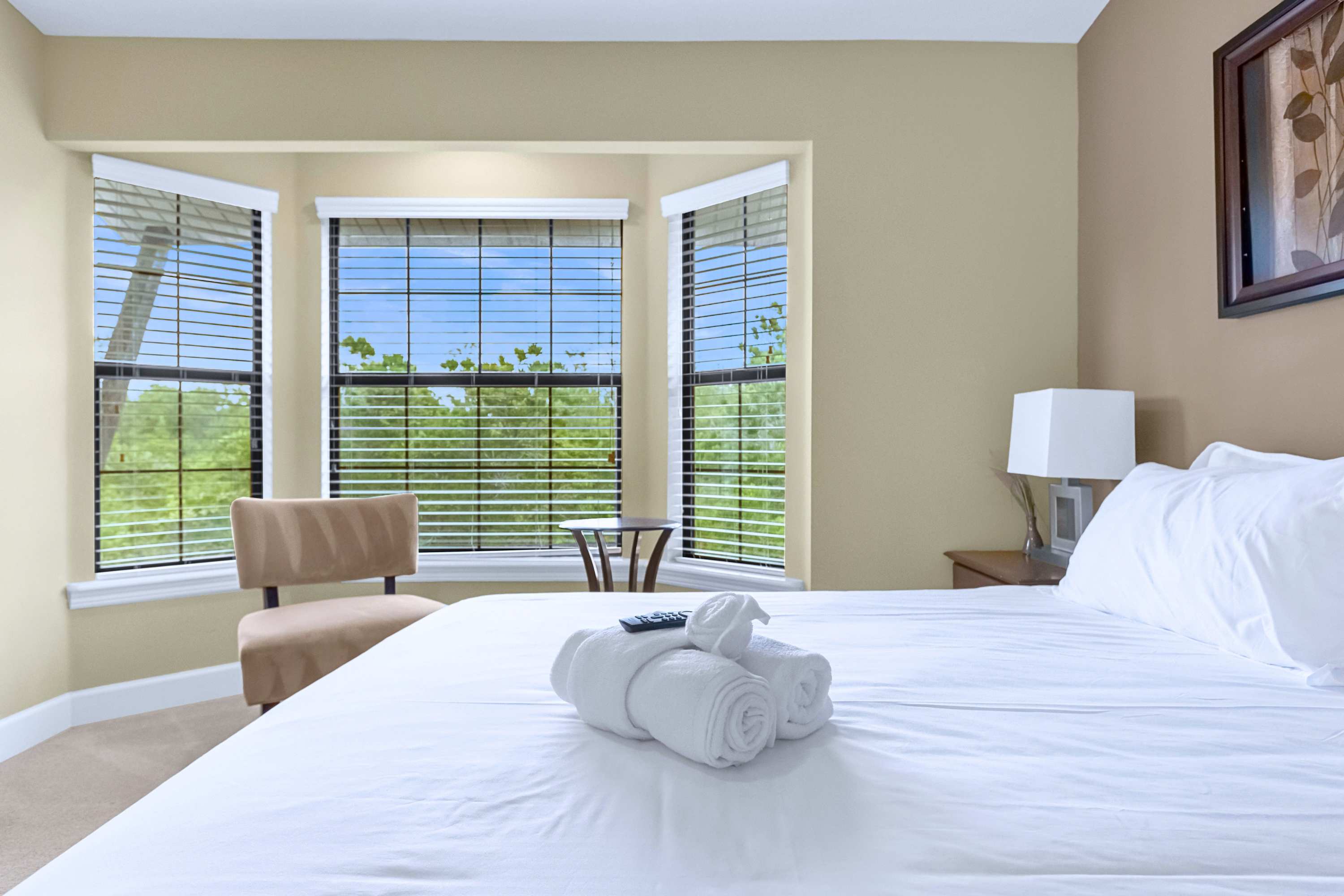 A bright guest bedroom featuring a cozy bay window sitting area