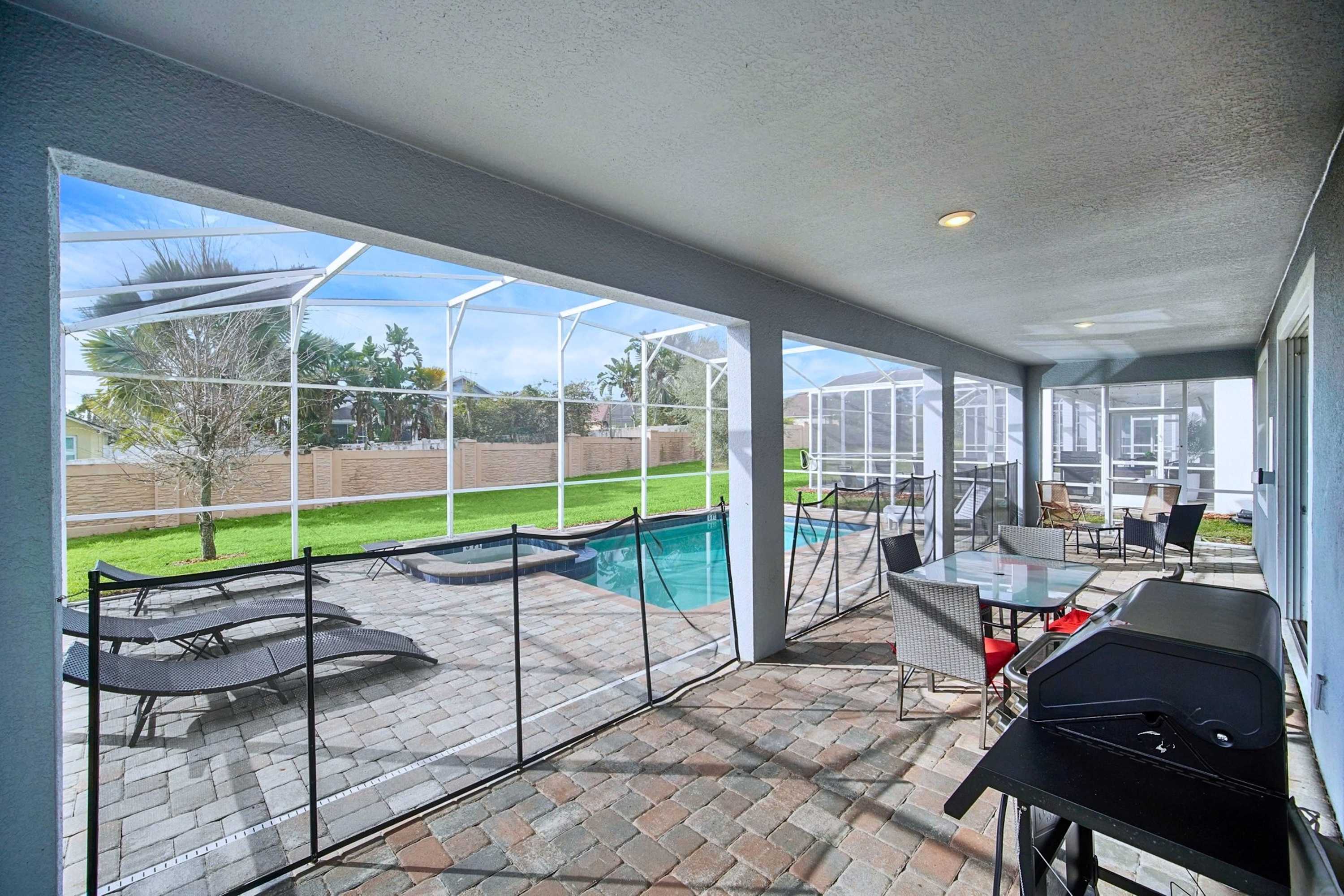 Pool area with outdoor lounge seating, dining area, and BBQ grill for poolside gatherings.