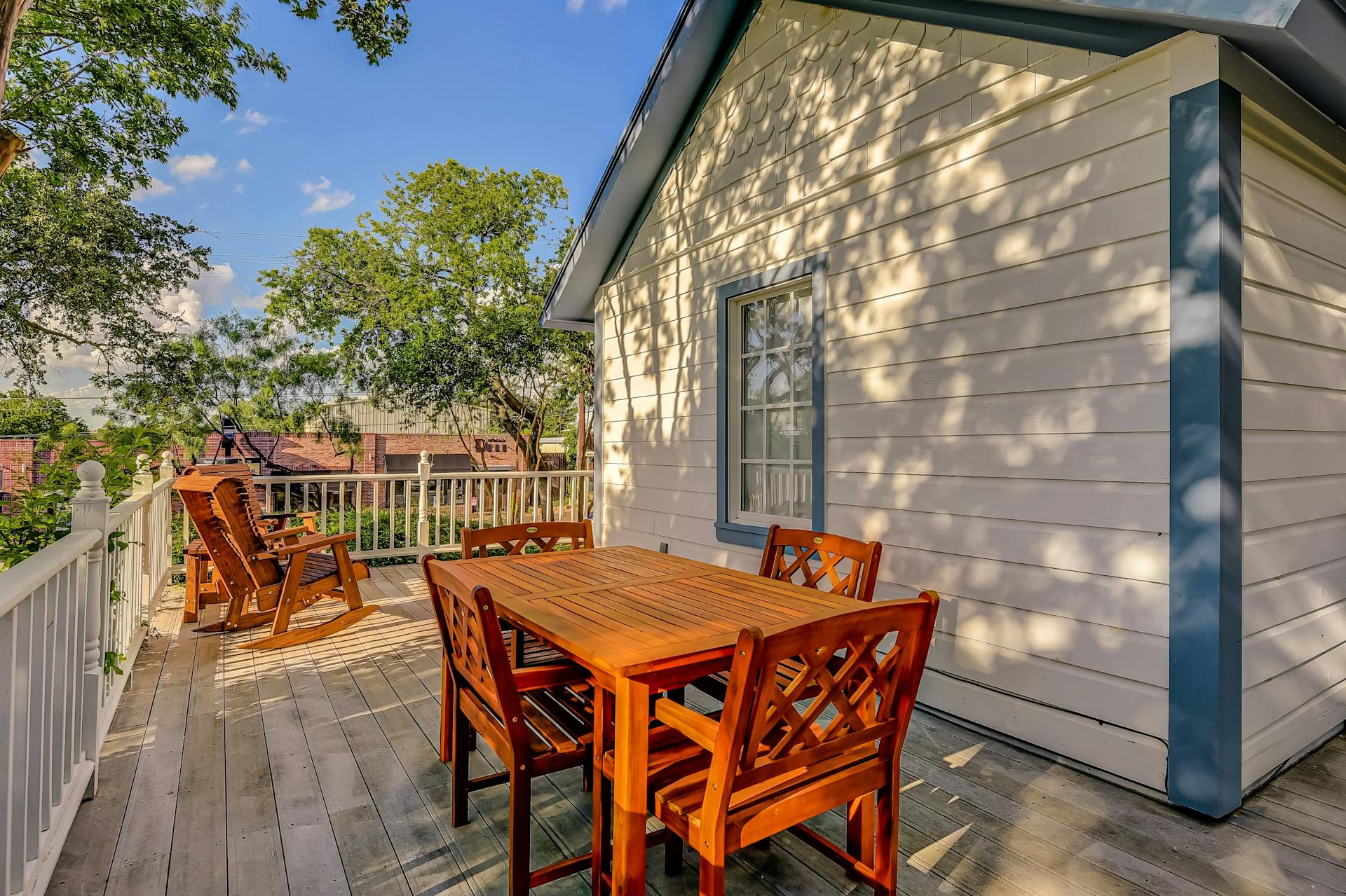 Enjoy serene outdoor dining on a private sunlit deck surrounded by lush trees and sunset views.