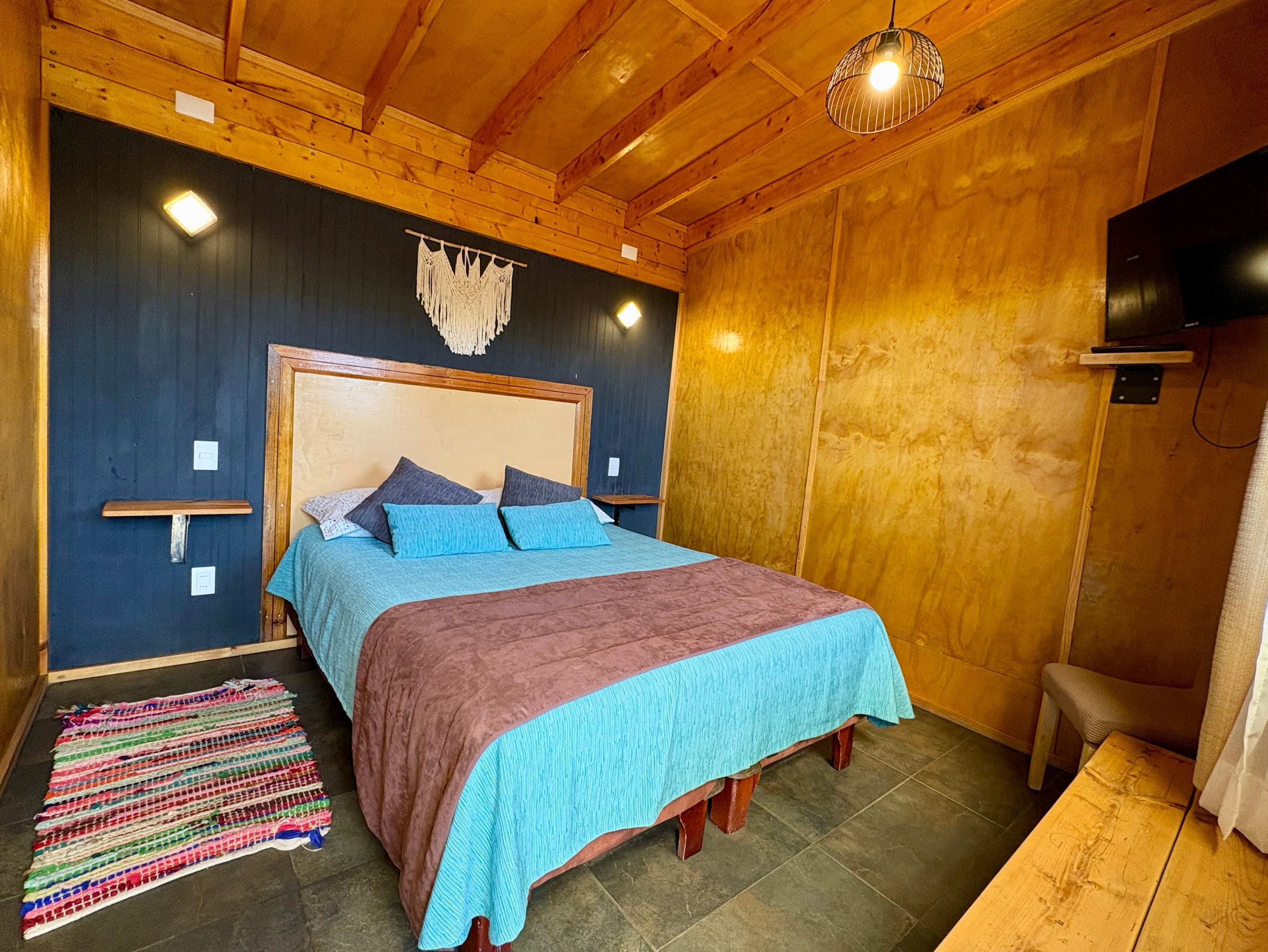 Private room with double bed, wood-panelled walls and TV