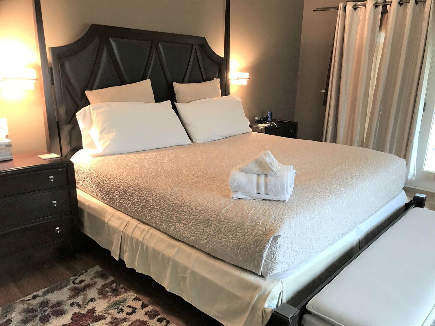 King bedroom with comfortable linens and bedside lamps