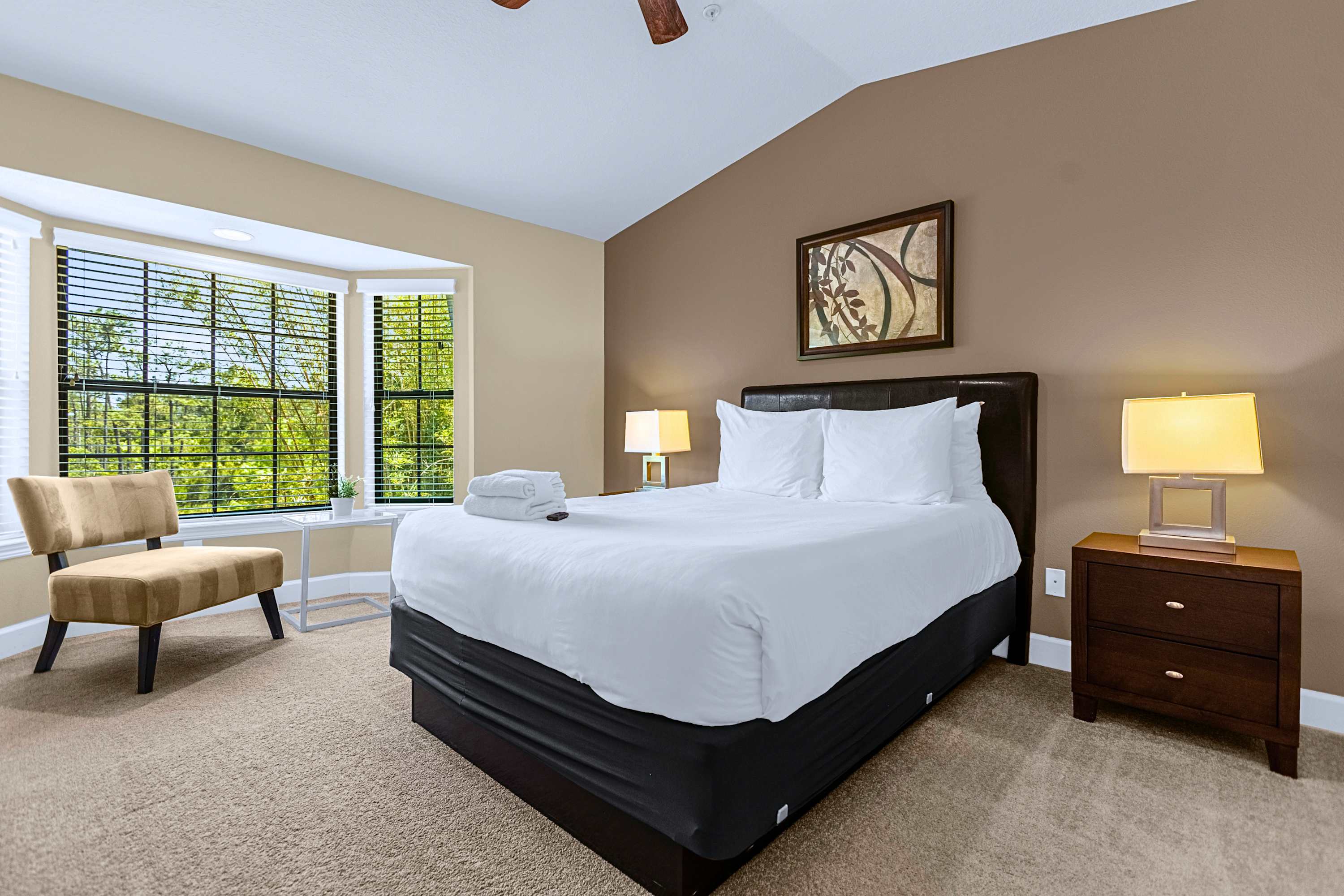 A bright guest bedroom featuring a cozy bay window sitting area