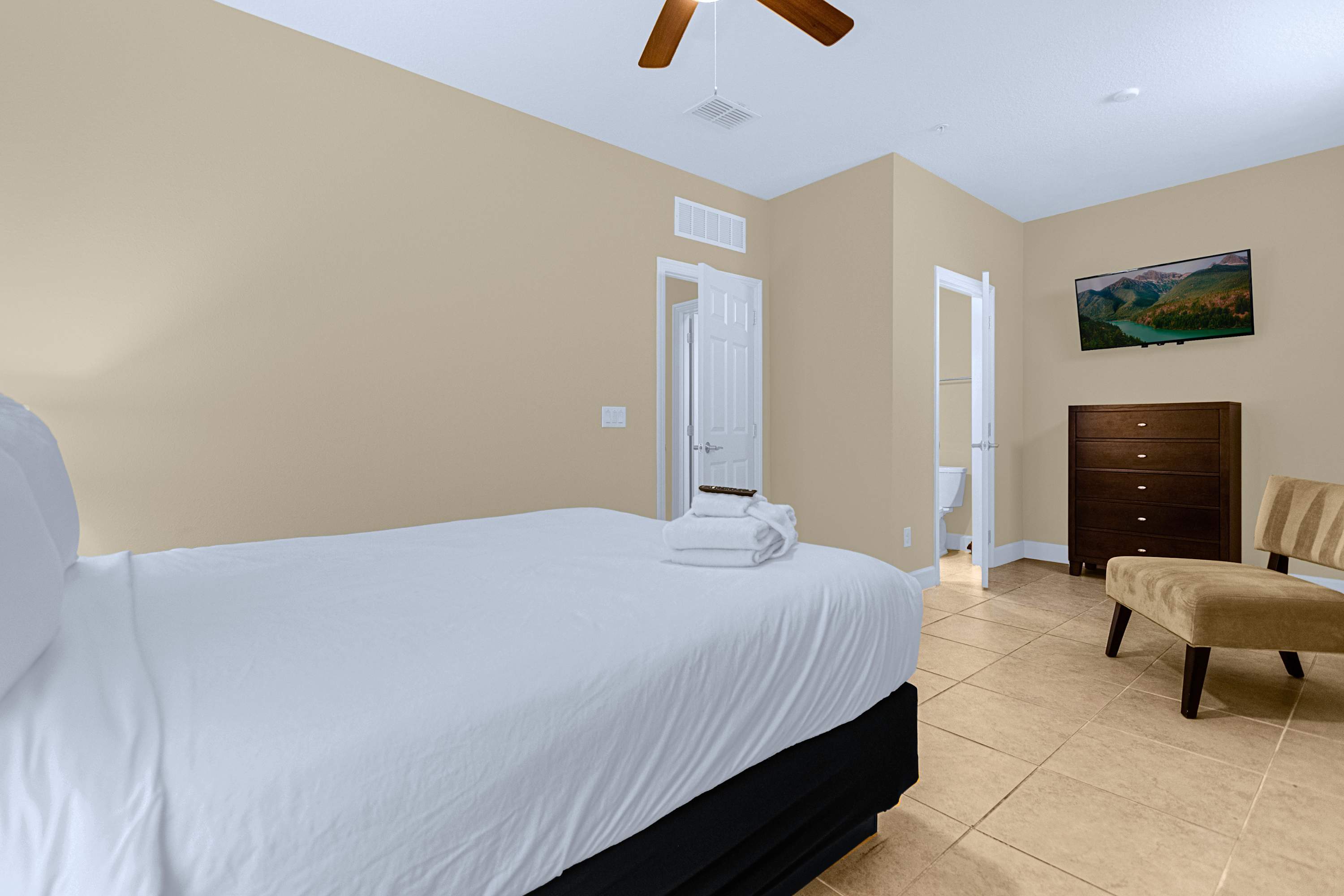 A peaceful guest bedroom featuring crisp white linens and a wall-mounted TV