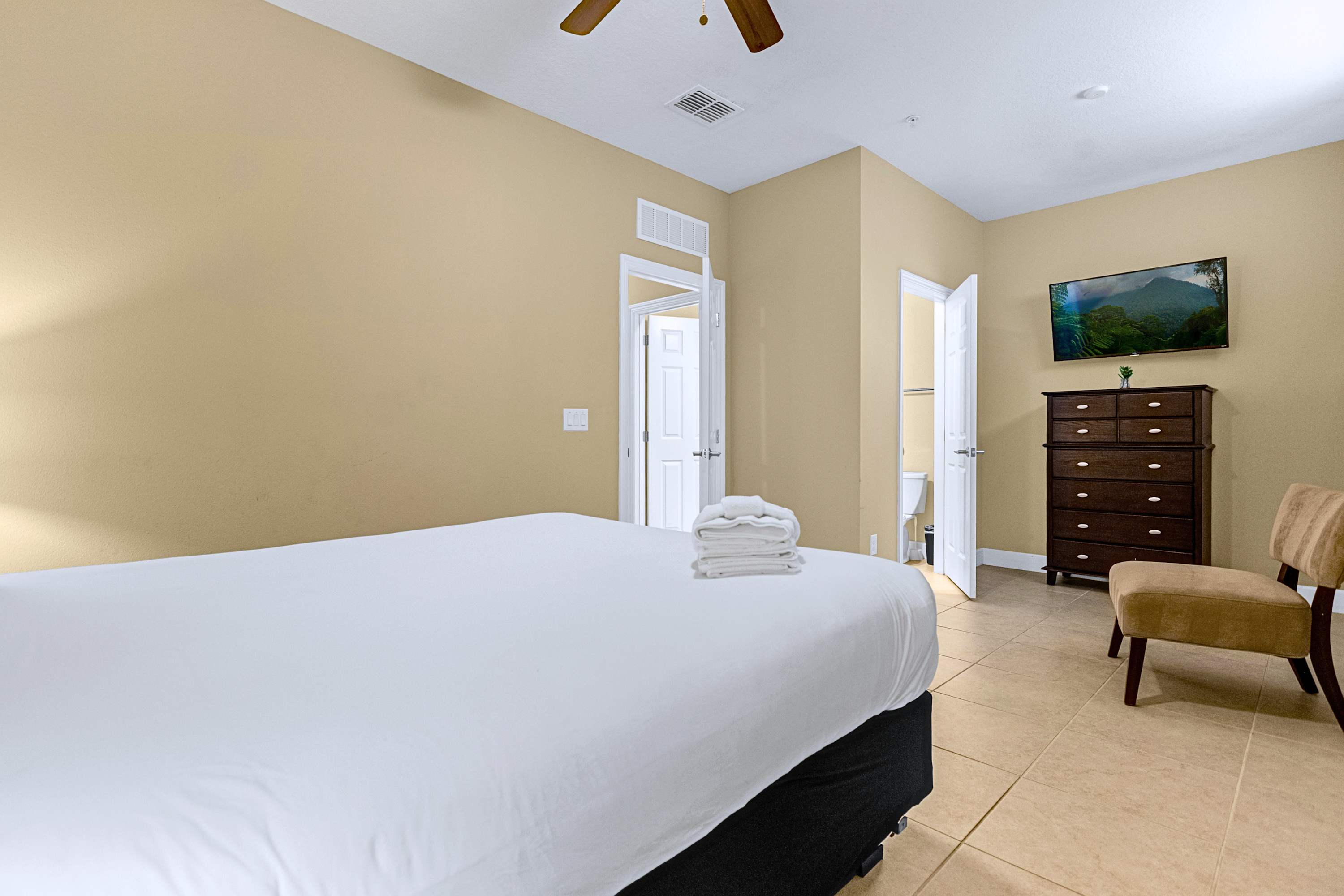 A peaceful guest bedroom featuring crisp white linens and a wall-mounted TV