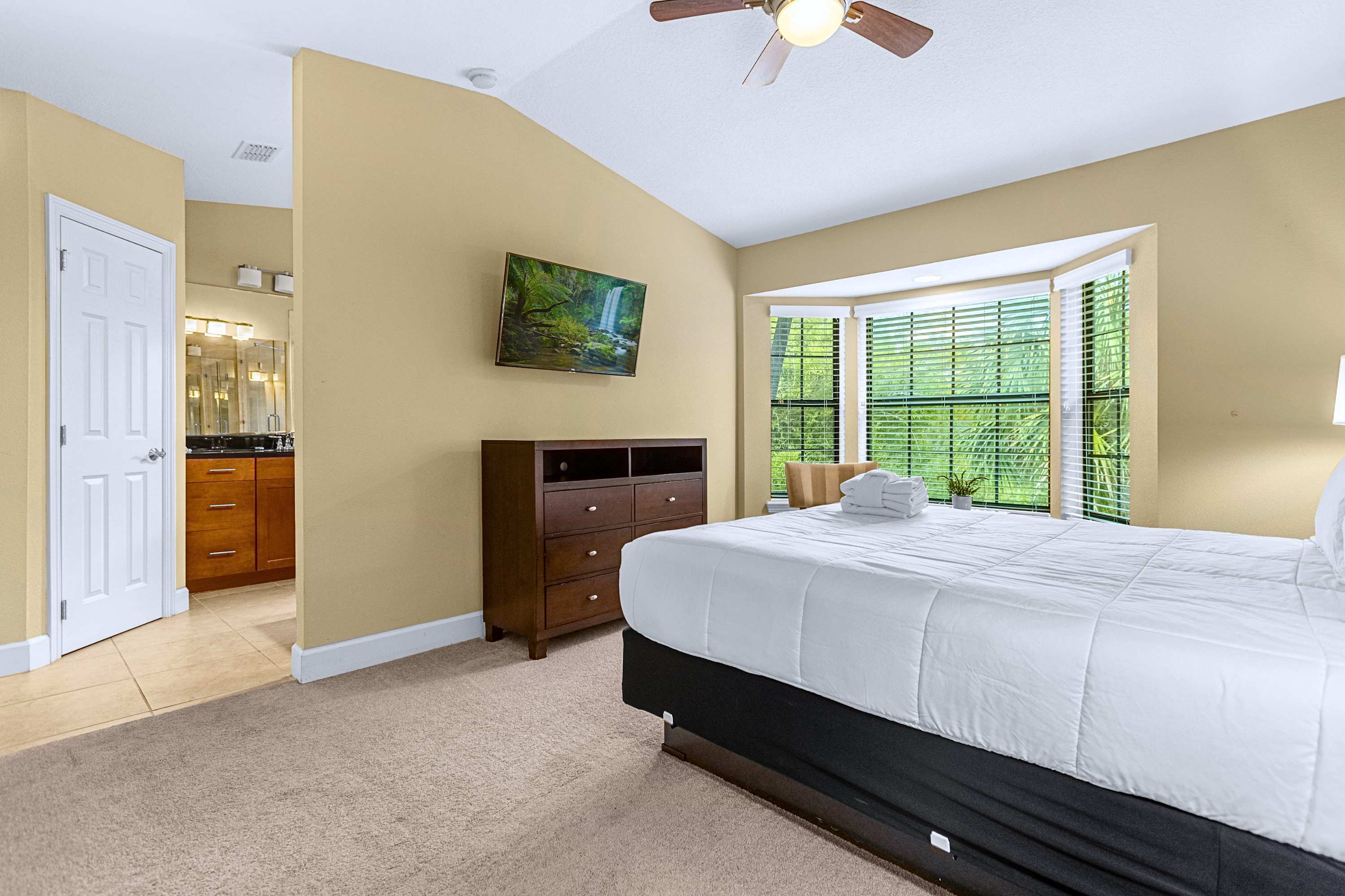 A bright guest bedroom featuring a cozy bay window sitting area