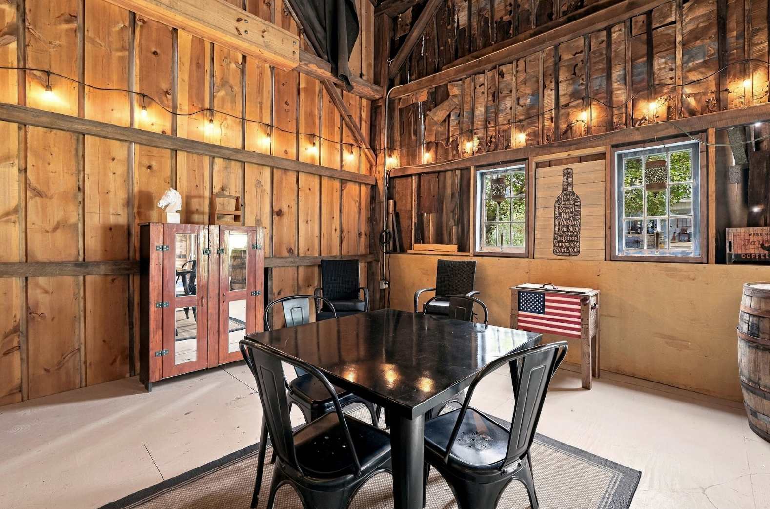 Café table for four under string lights in a Harbor Country barn.