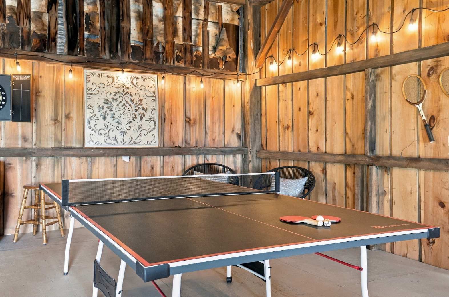 Ping pong and darts in the barn with paddles ready to play.