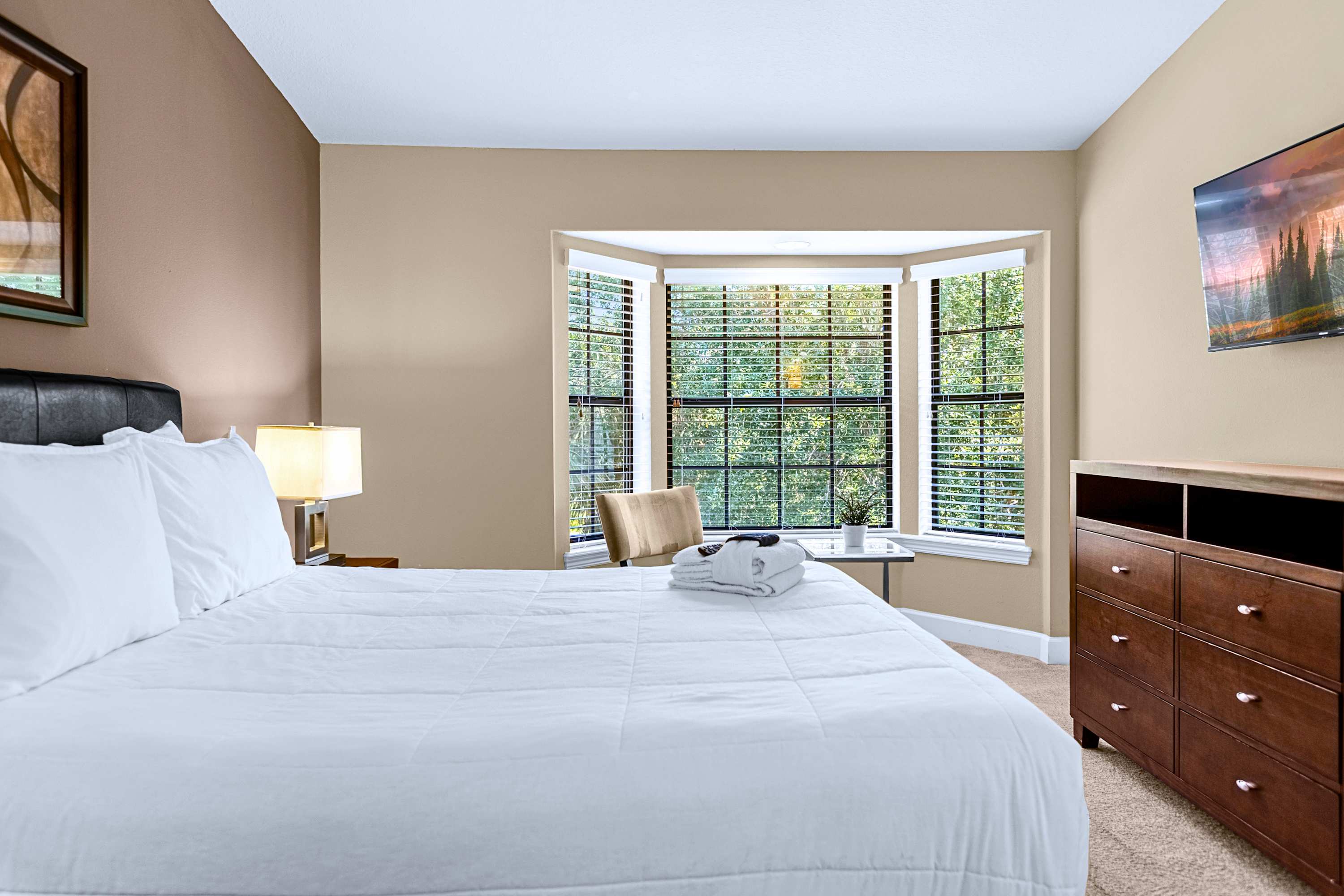 A bright guest bedroom featuring a cozy bay window sitting area