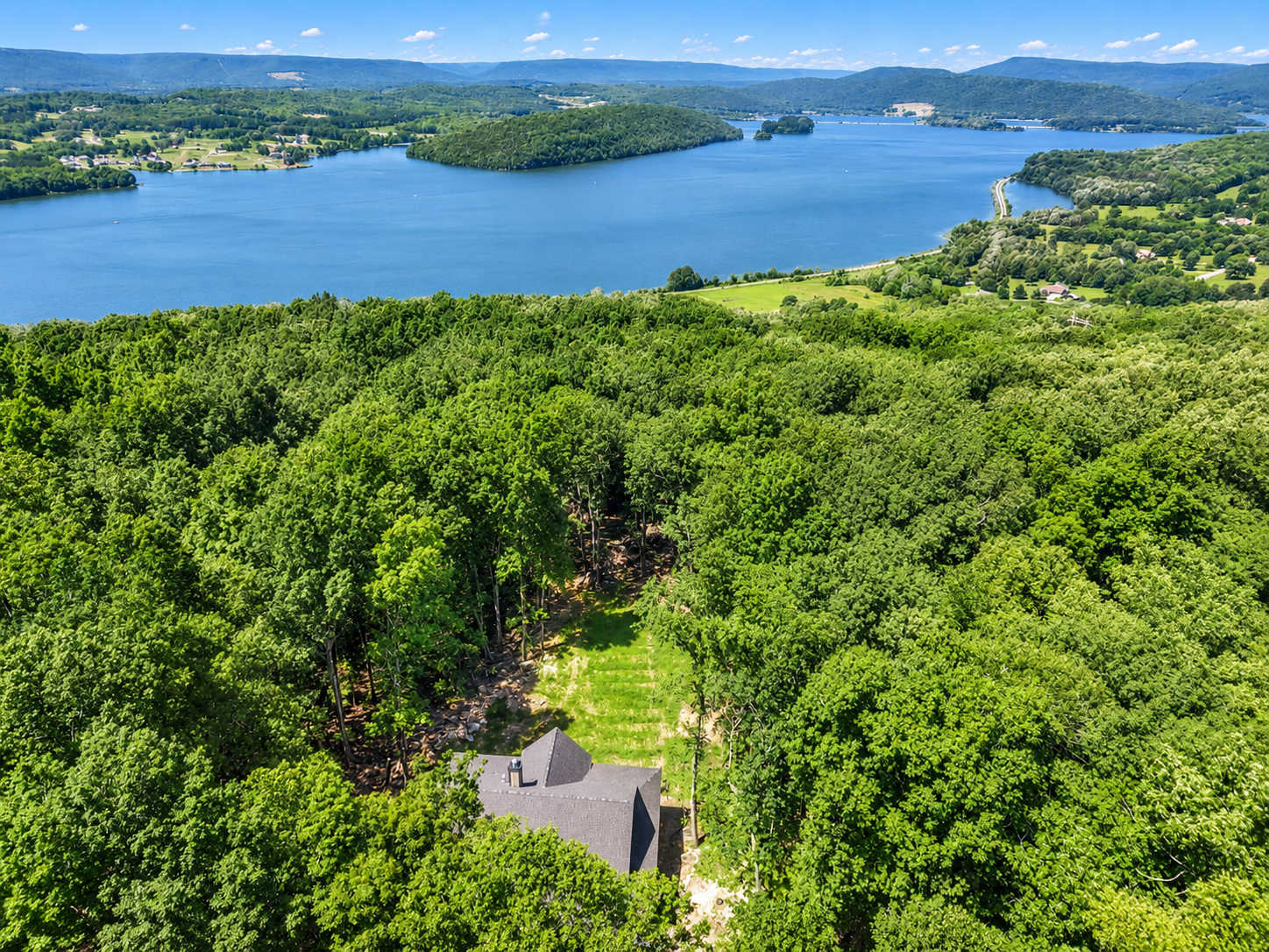 An aerial view of the lodge, woodland, and water beyond