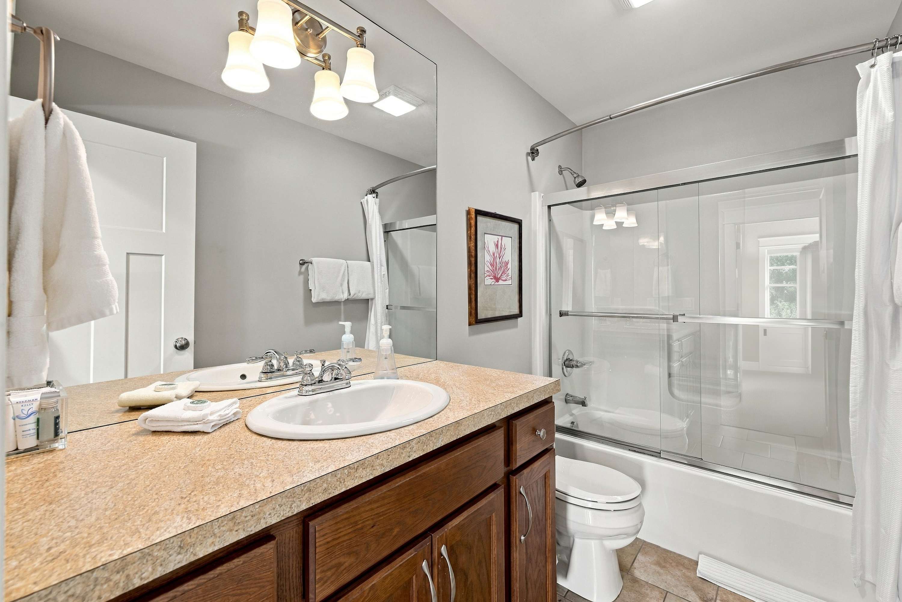 Rinse off the beach sand in a tub and shower combo with glass doors.
