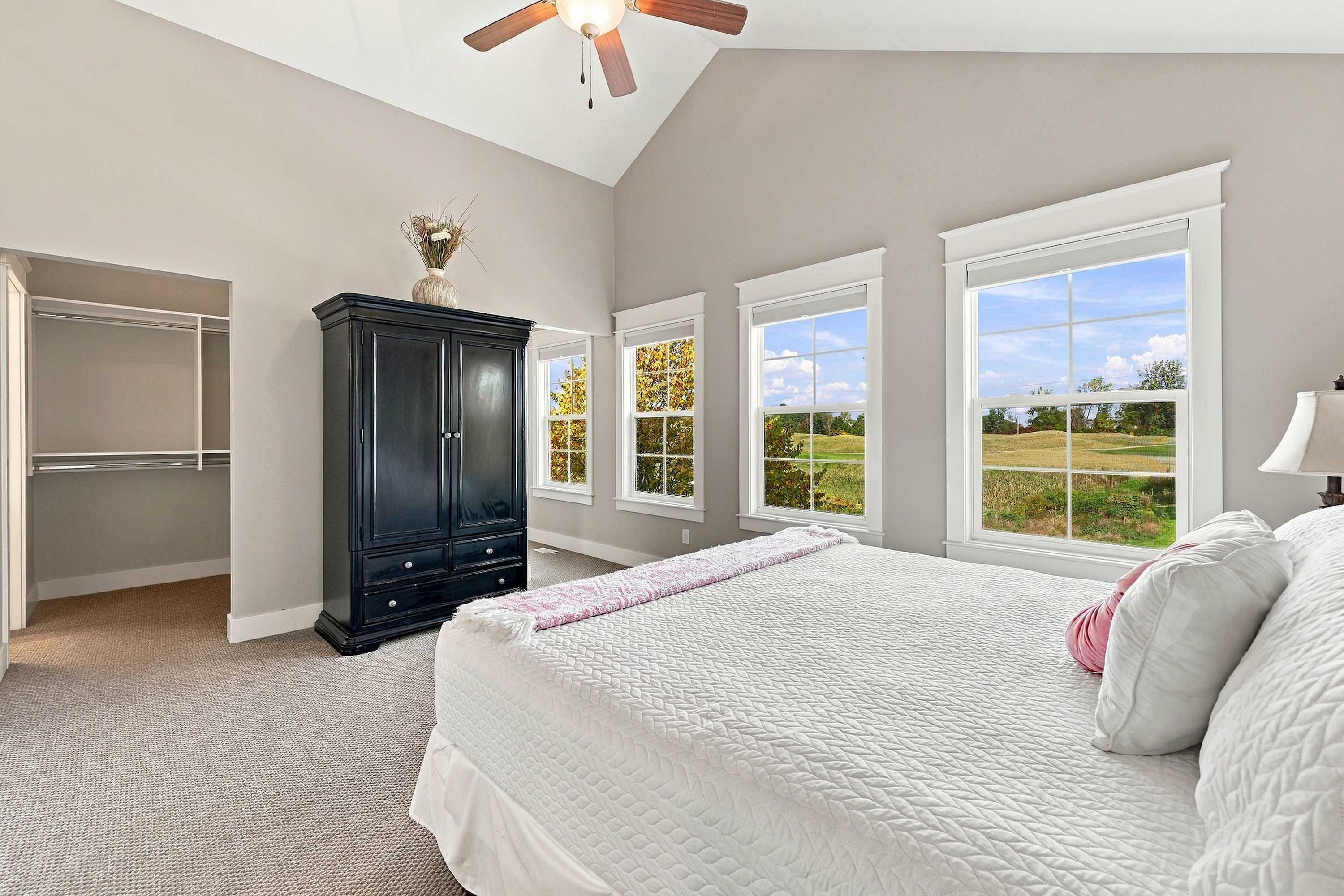 A vaulted main bedroom with a ceiling fan, armoire, and roomy closet.