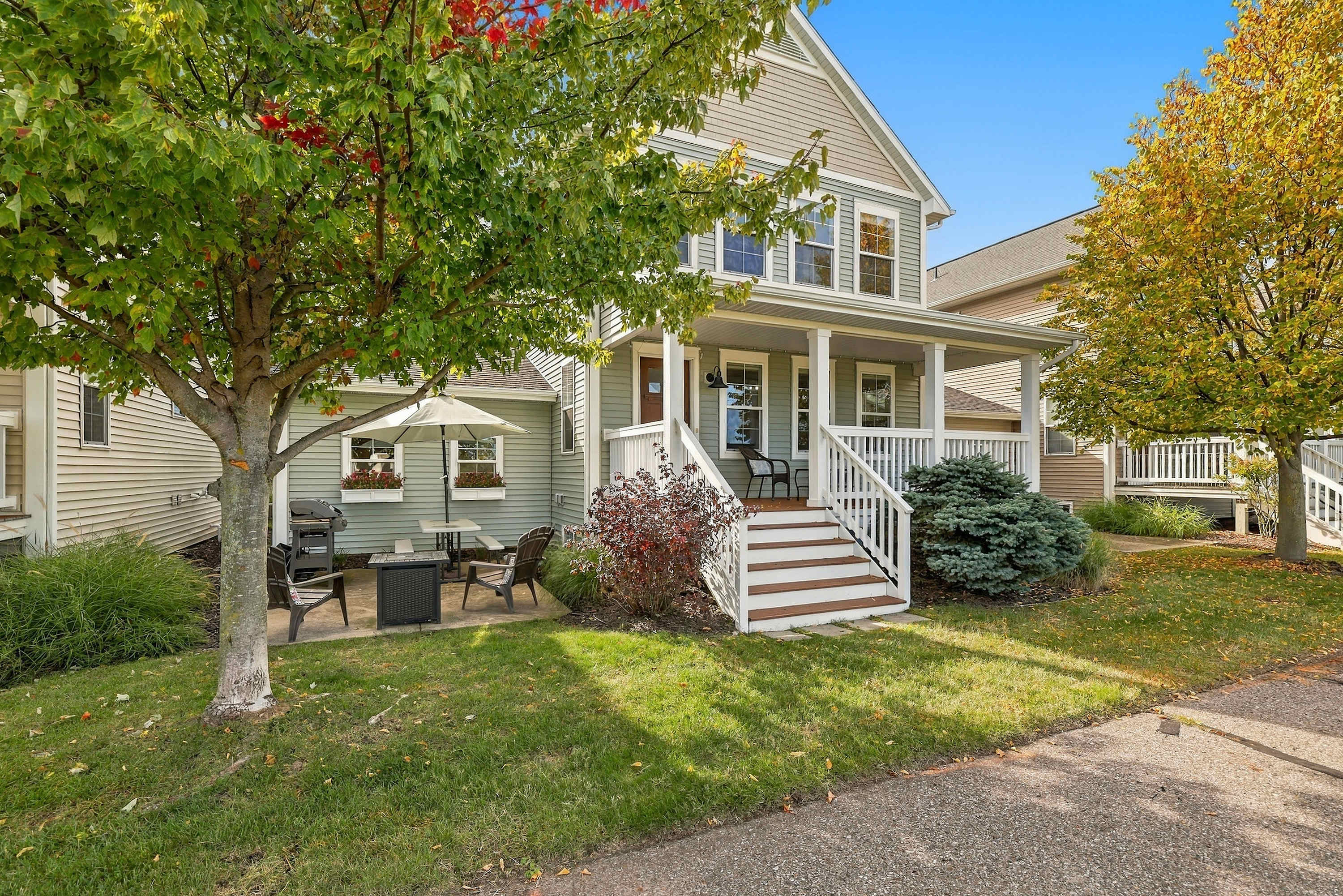 Fall color frames this sage green Benton Harbor home and its front porch.