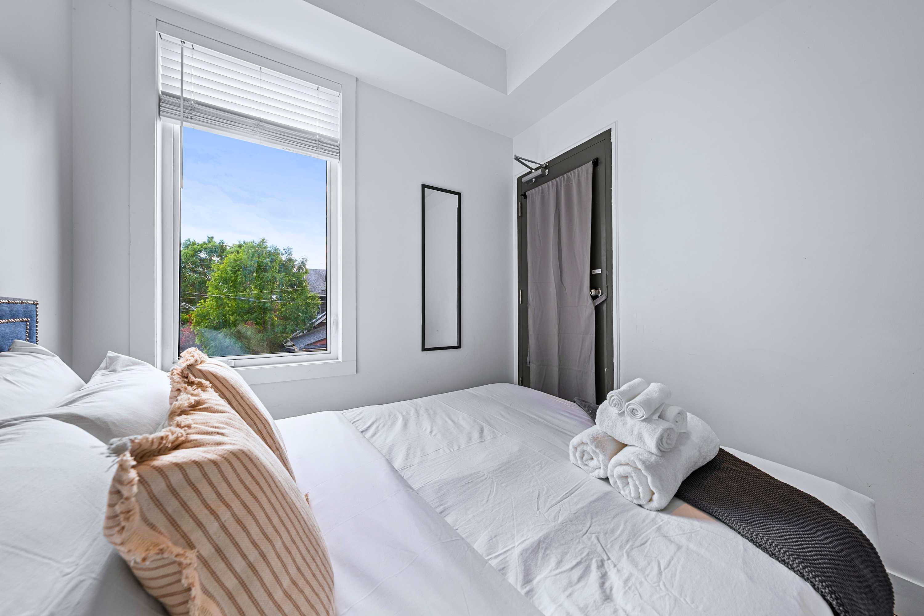 Inviting guest bedroom offering sunlit window views and comfortable bedding