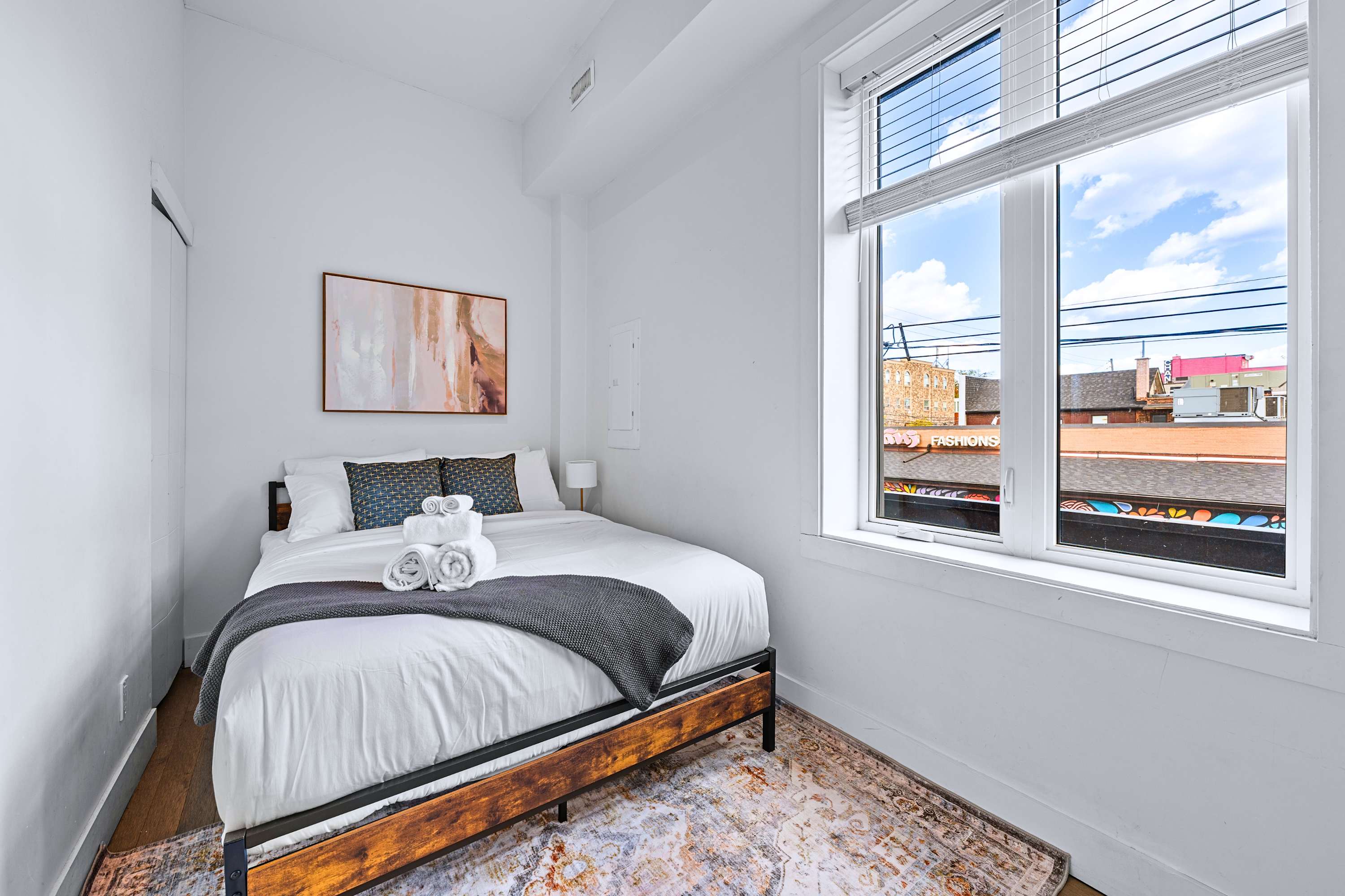 A calm guest bedroom featuring a metal bed frame, plush pillows, and sunlight
