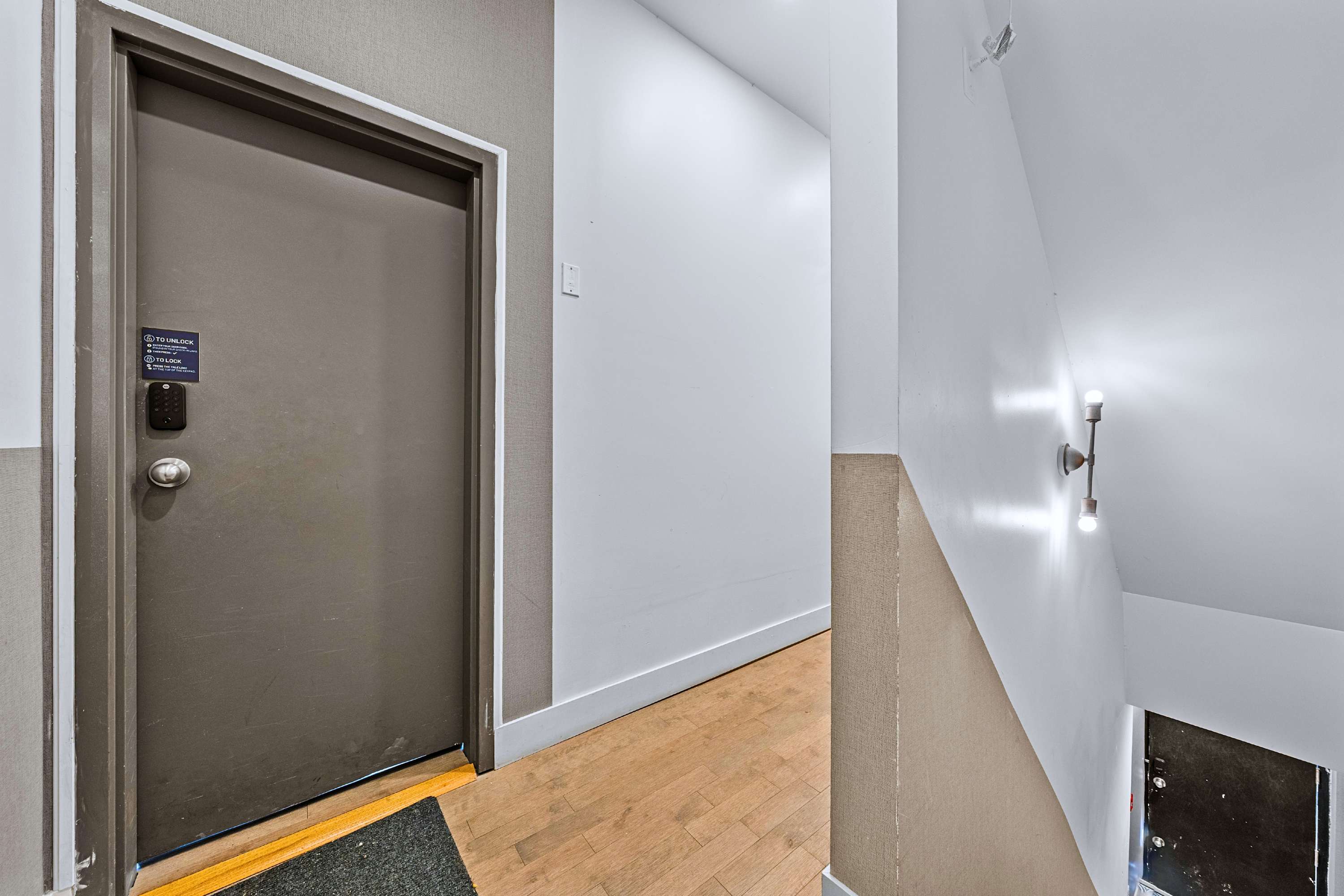 A secure private unit entryway opening into a clean, modern hallway