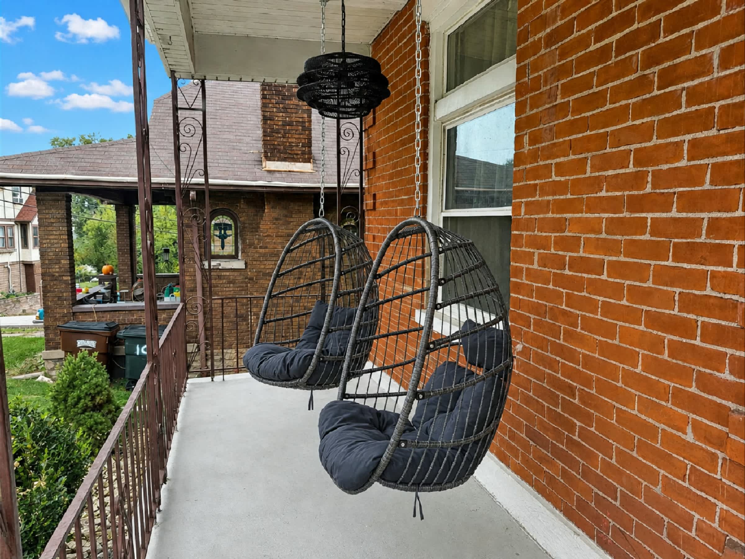 Relax on the charming covered brick porch featuring comfortable hanging chairs, a cozy spot to enjoy your morning coffee, fresh air, or a peaceful evening outdoors.