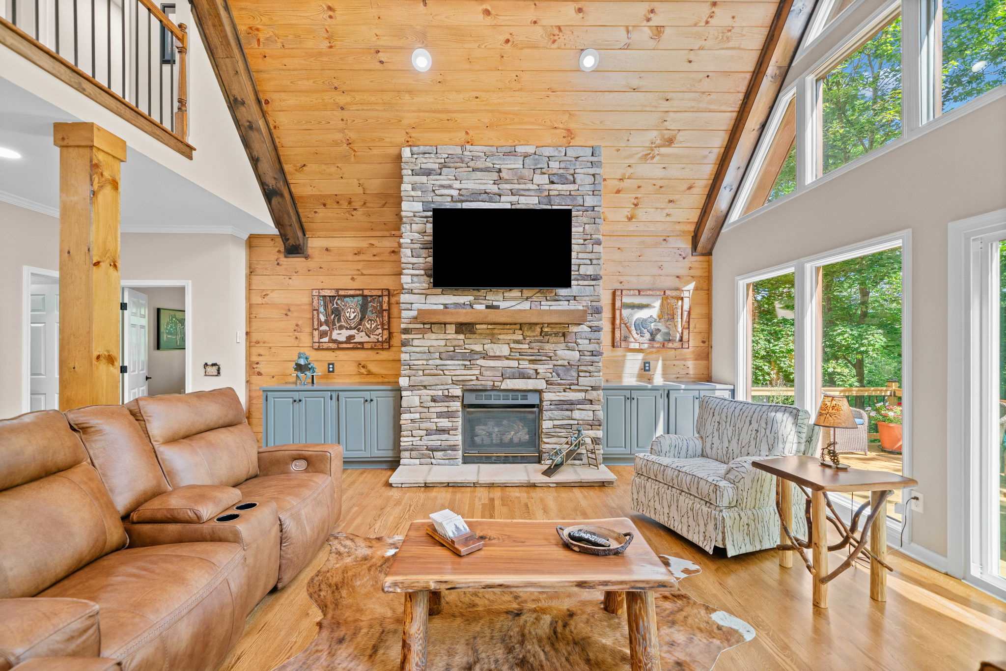 Relax in the open living room with soaring ceilings, wall-to-wall windows, cozy couches, and a Smart TV​
