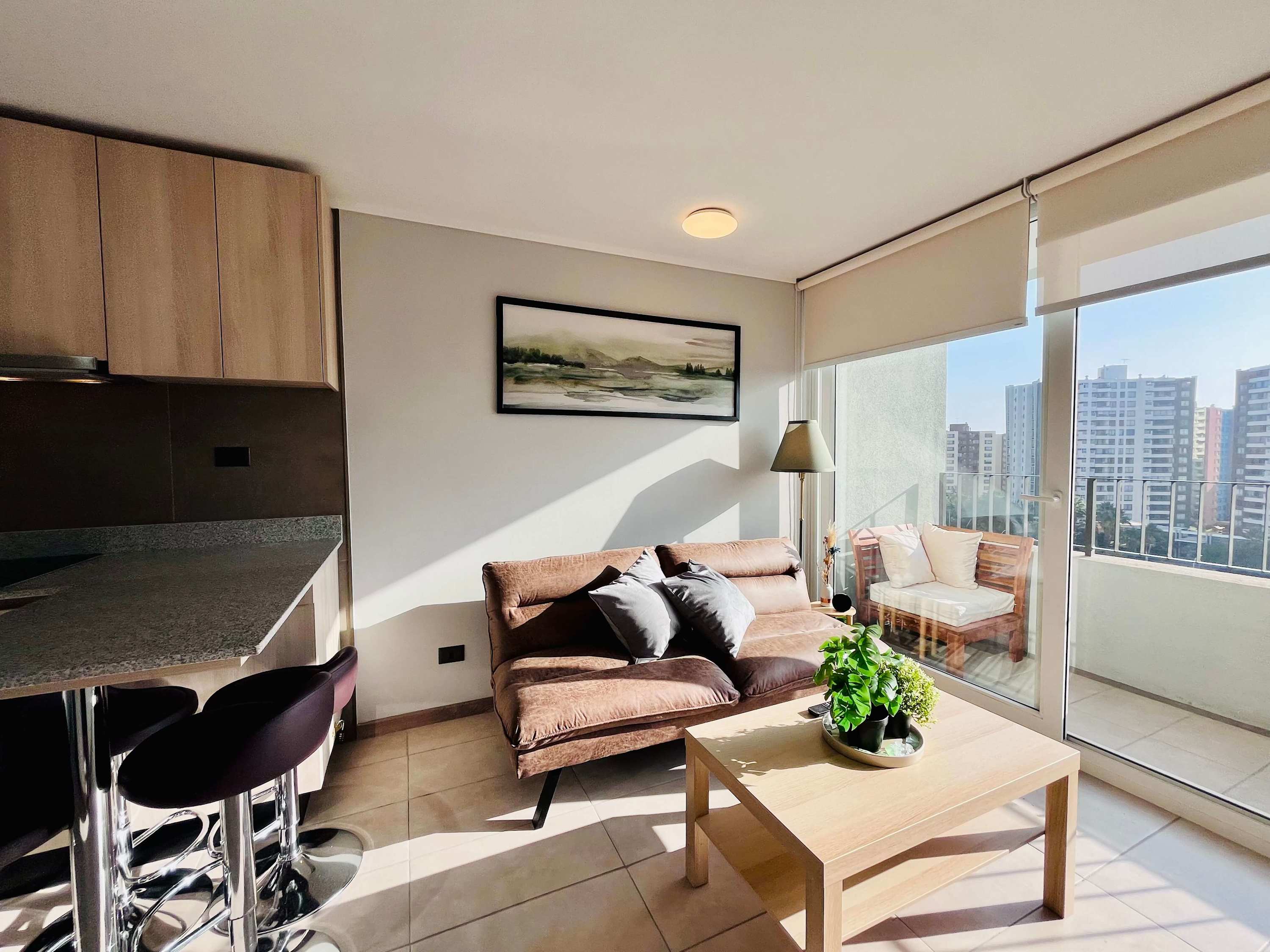 Bright living room with sofa, kitchen bar and balcony access