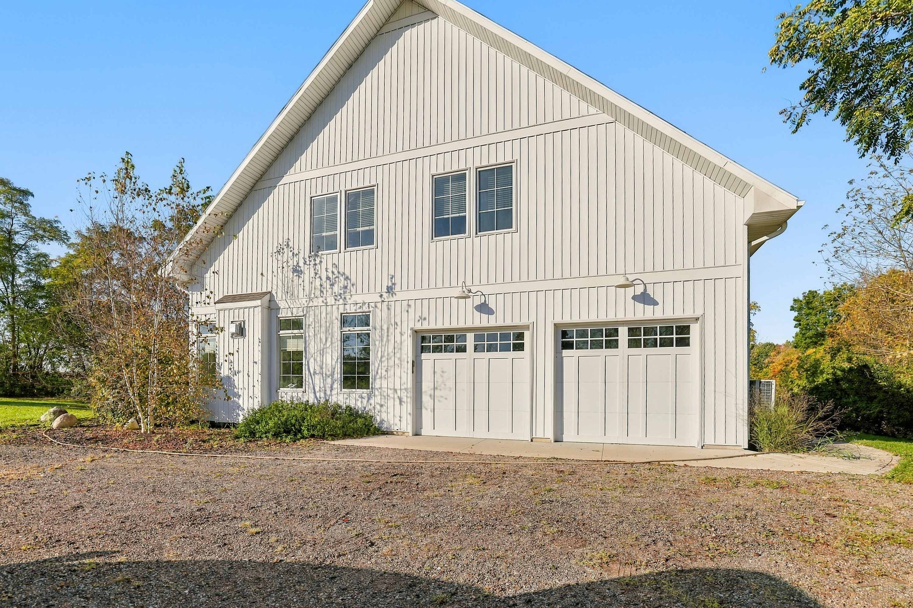Three Oaks barn home with a double garage and plenty of gravel parking.