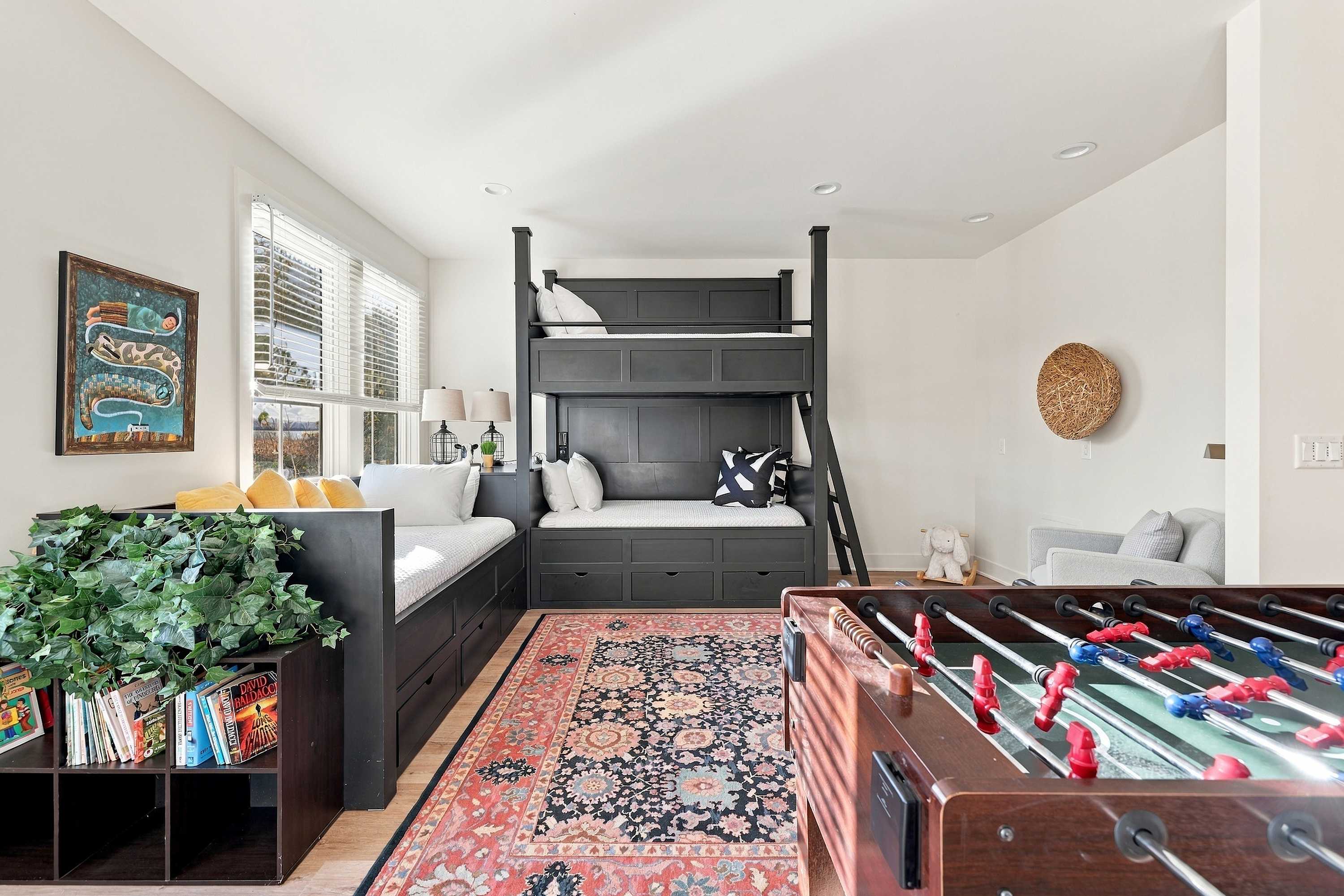 A Three Oaks bunk room with custom bunks, a daybed, and a foosball table.