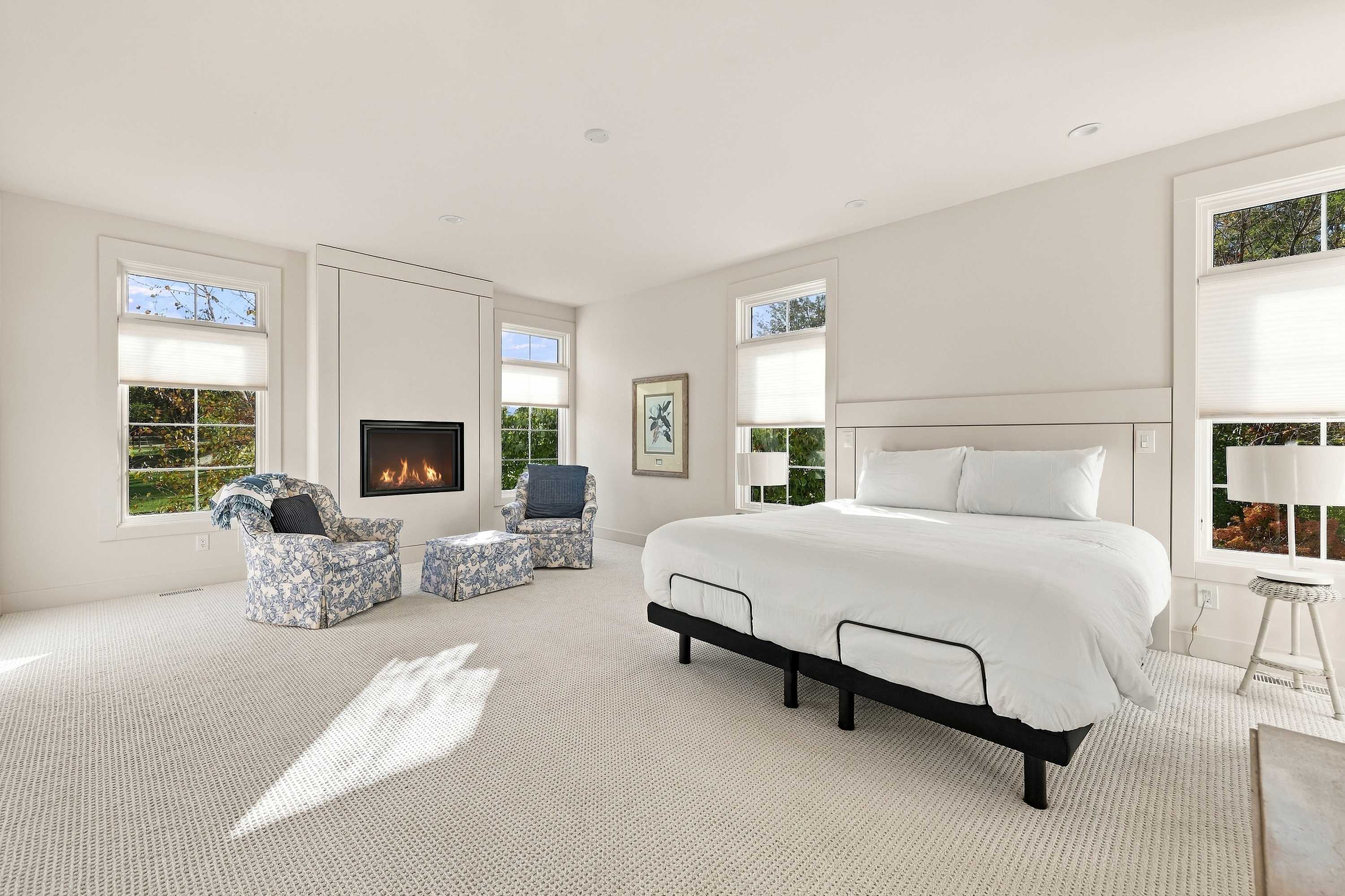 Master bedroom with a fireplace, king bed, and armchairs.