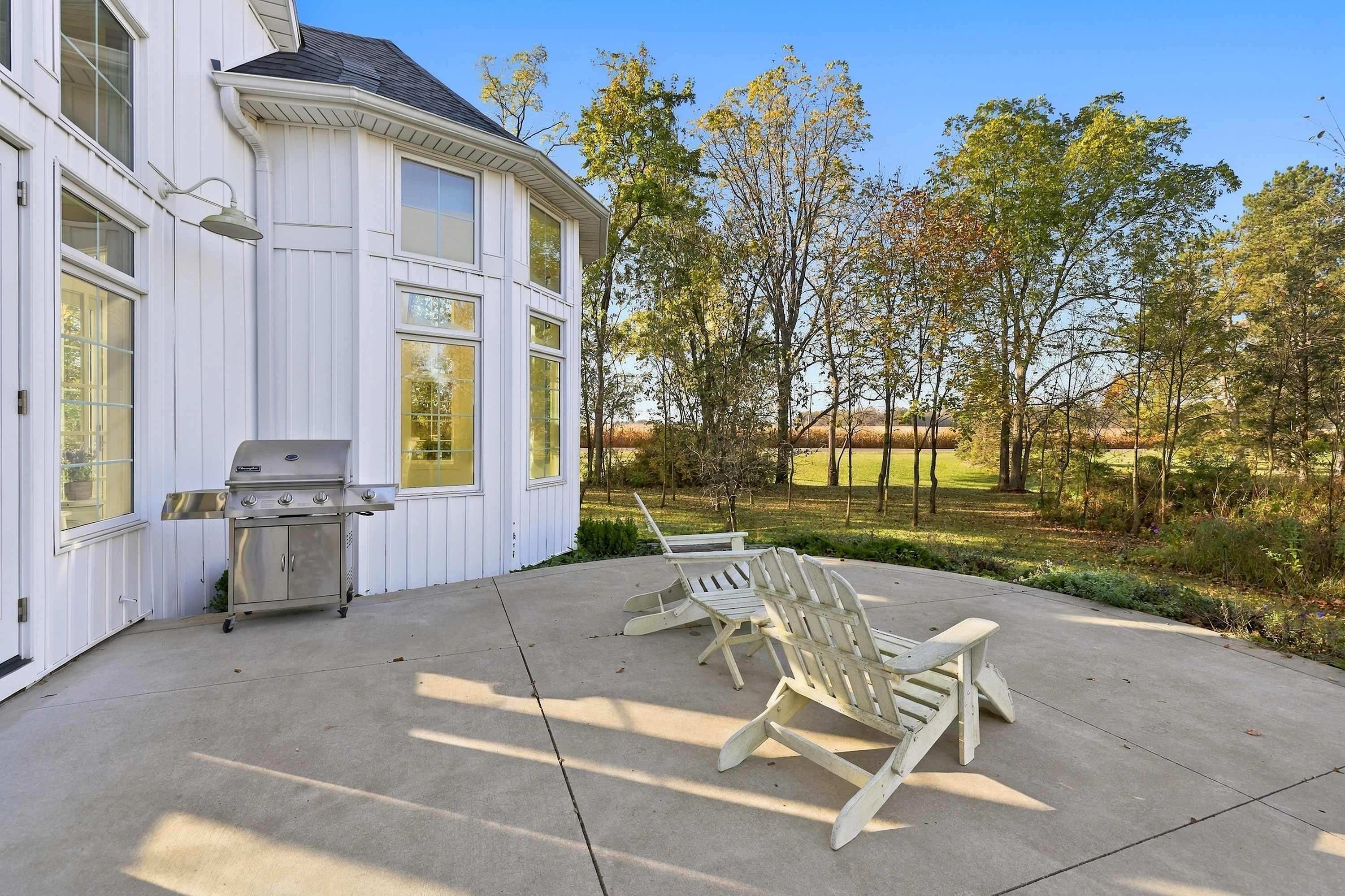 A sunny Three Oaks patio with a gas grill and seating beside the turret.