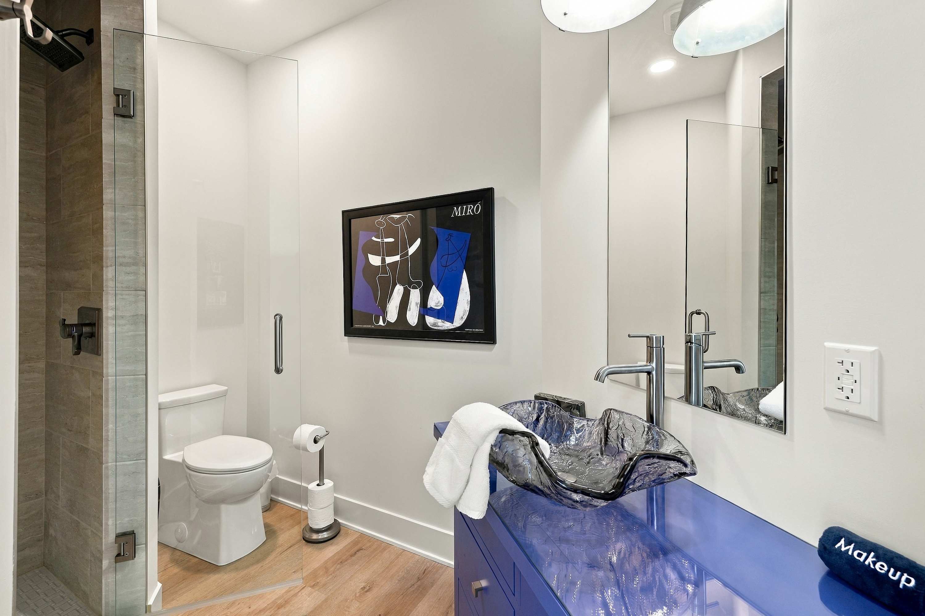 Bathroom off the sunlit office, with a rain shower and glass sink.