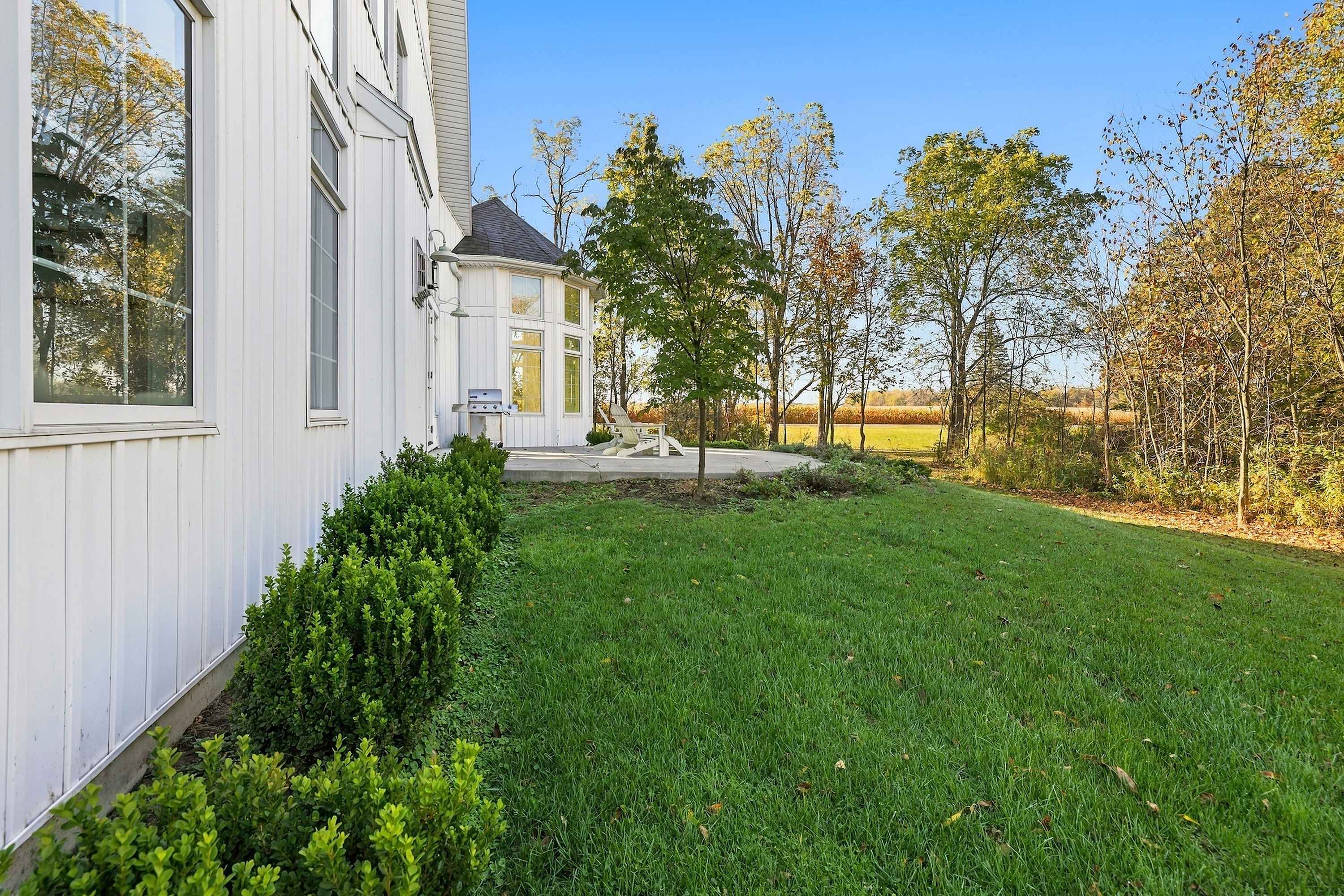 Harbor Country home with a manicured lawn, boxwood hedges, and field views.