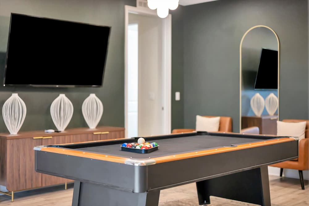 Pool table positioned beneath a wall-mounted TV