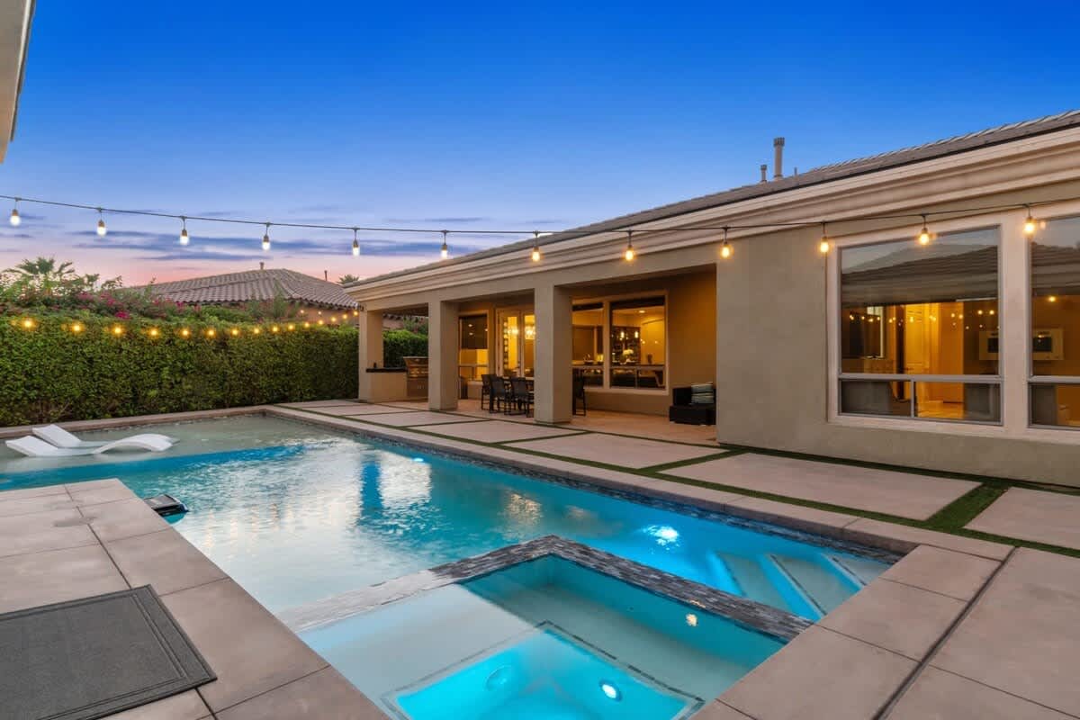 Pool and spa glow at dusk under string lights.