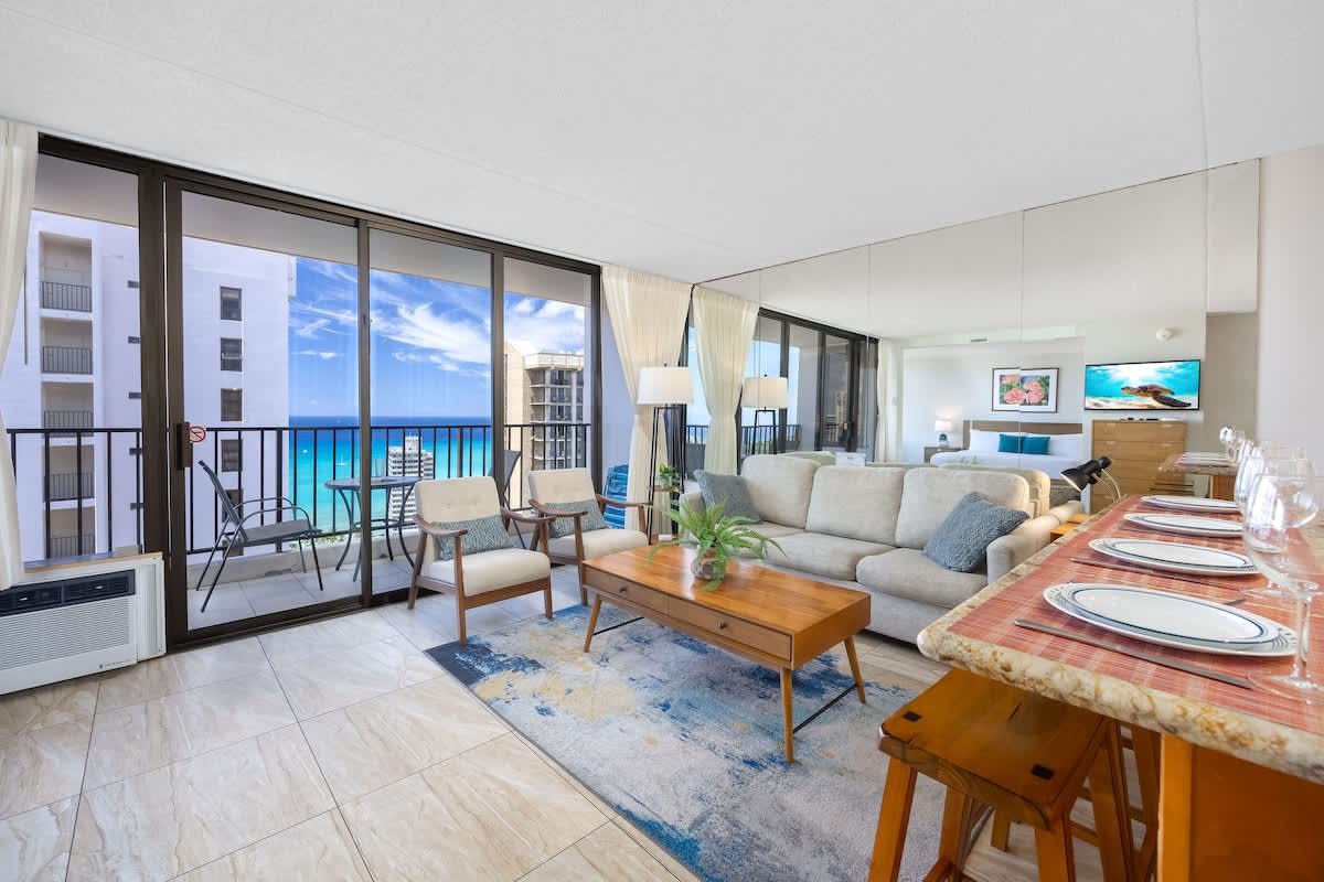 Spacious living area bathed in natural light w/ floor-to-ceiling windows.
