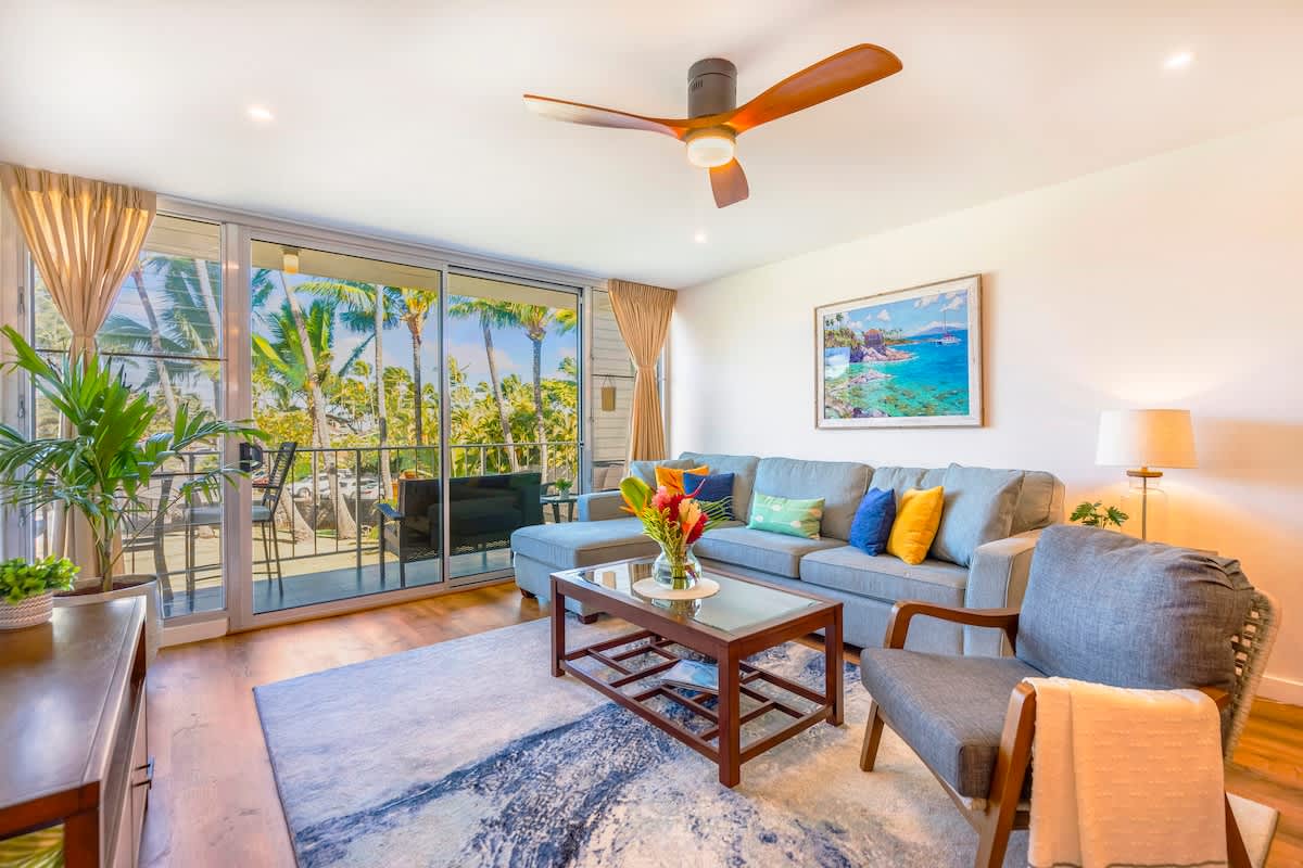 Step into this bright and airy living space, where a comfortable sectional sofa and sliding glass doors open to a private balcony with tropical views.