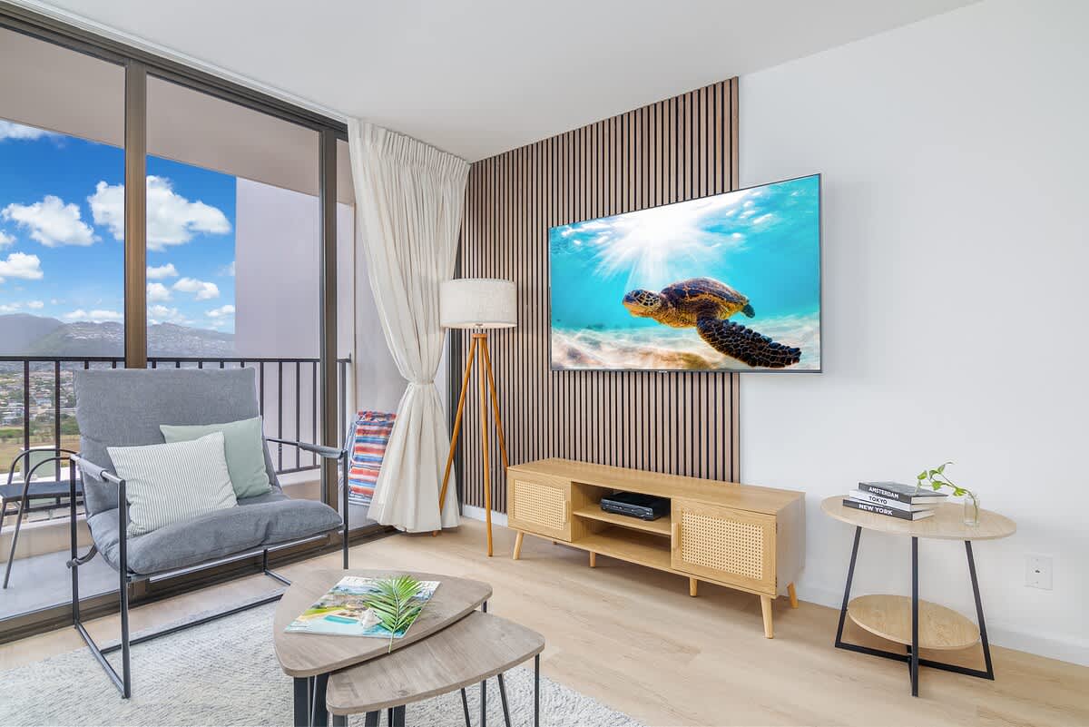 An elegant and cozy living space on the 26th floor, complete with a 65" smart TV for your entertainment, and a private balcony offering breathtaking mountain views – blending modern comfort with a tropical escape.