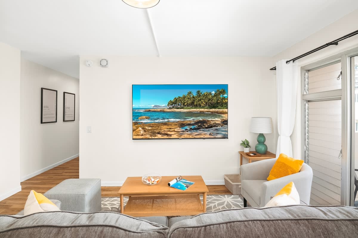 Living room with a queen-size pull-out sleeper sofa, a 75'' smart TV, and a beautiful mountain view.