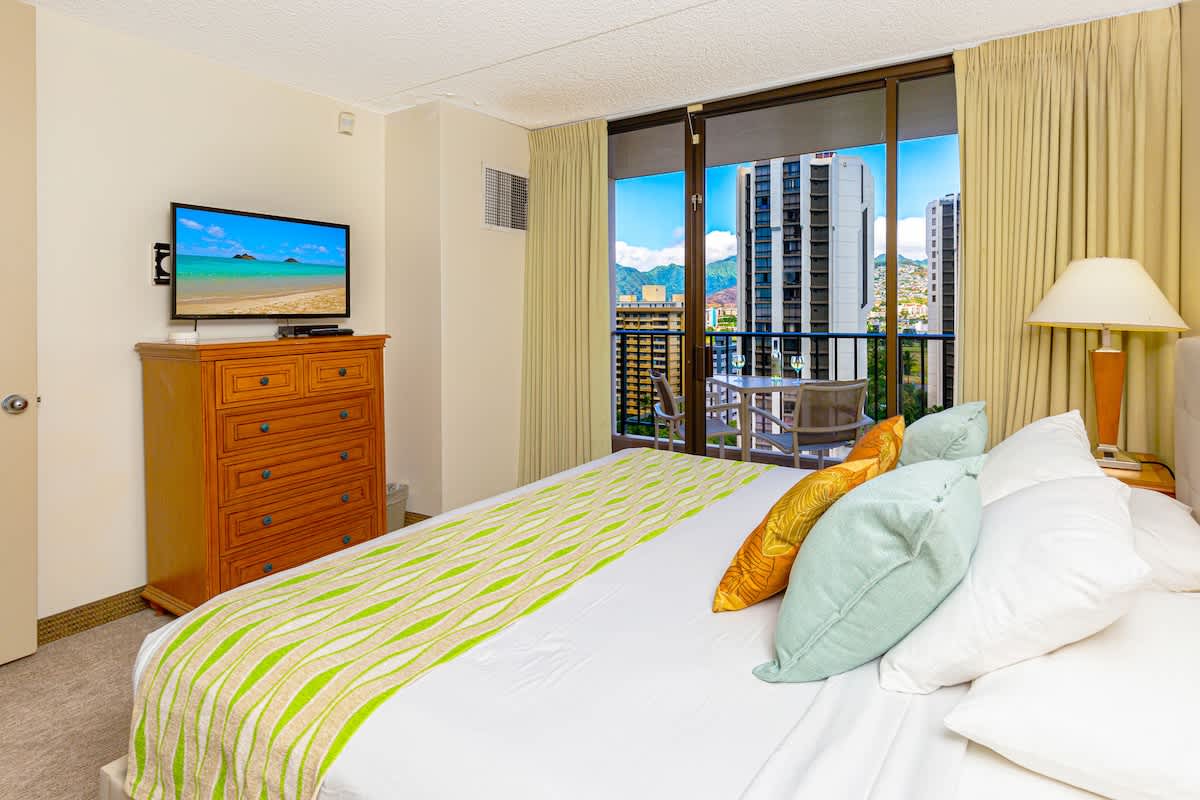 Relax in this bright bedroom with a balcony offering city and mountain views.