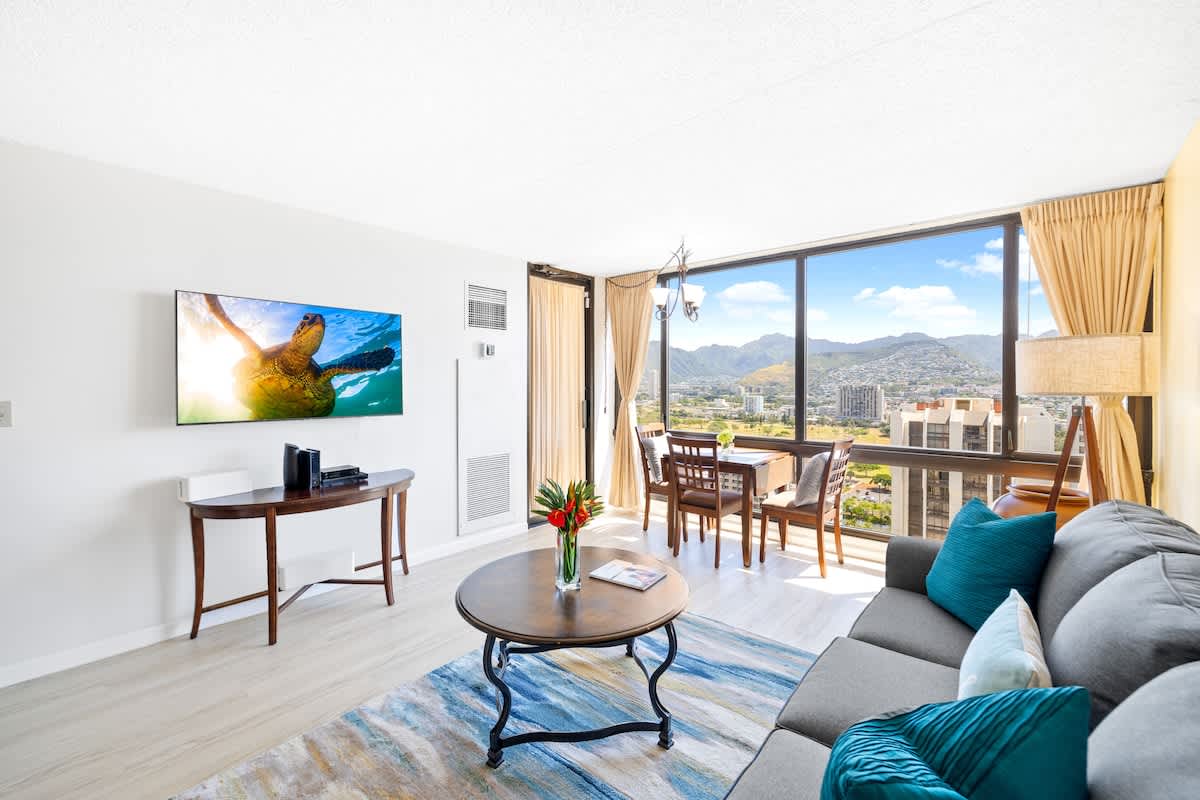Enjoy the spacious, light-filled living area with a 55" Smart TV and panoramic views of the city and mountains through your expansive windows.